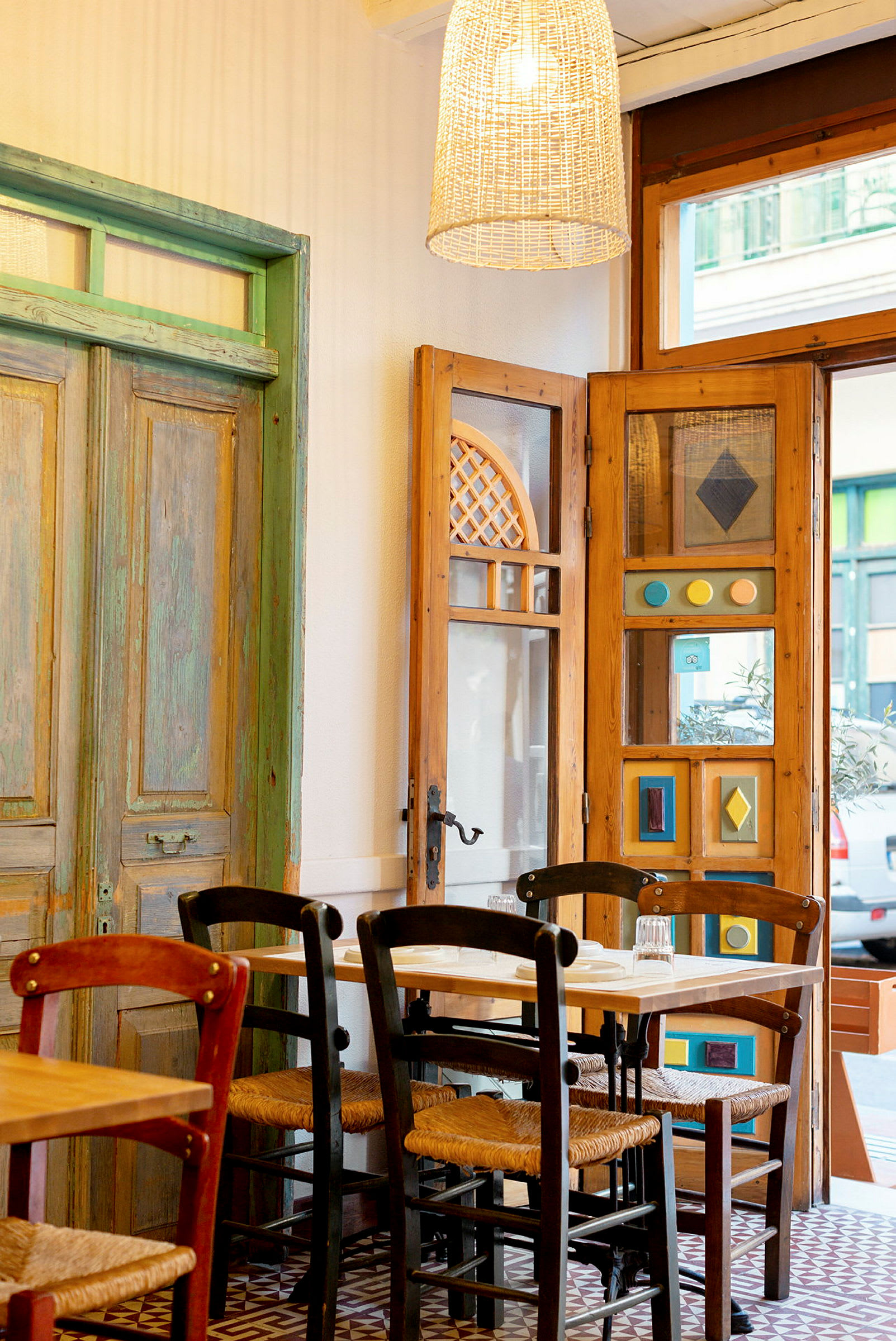 Interiøret i en restaurant med trestoler og et bord foran dekorative dører og vinduer. (AI-generert tekst)