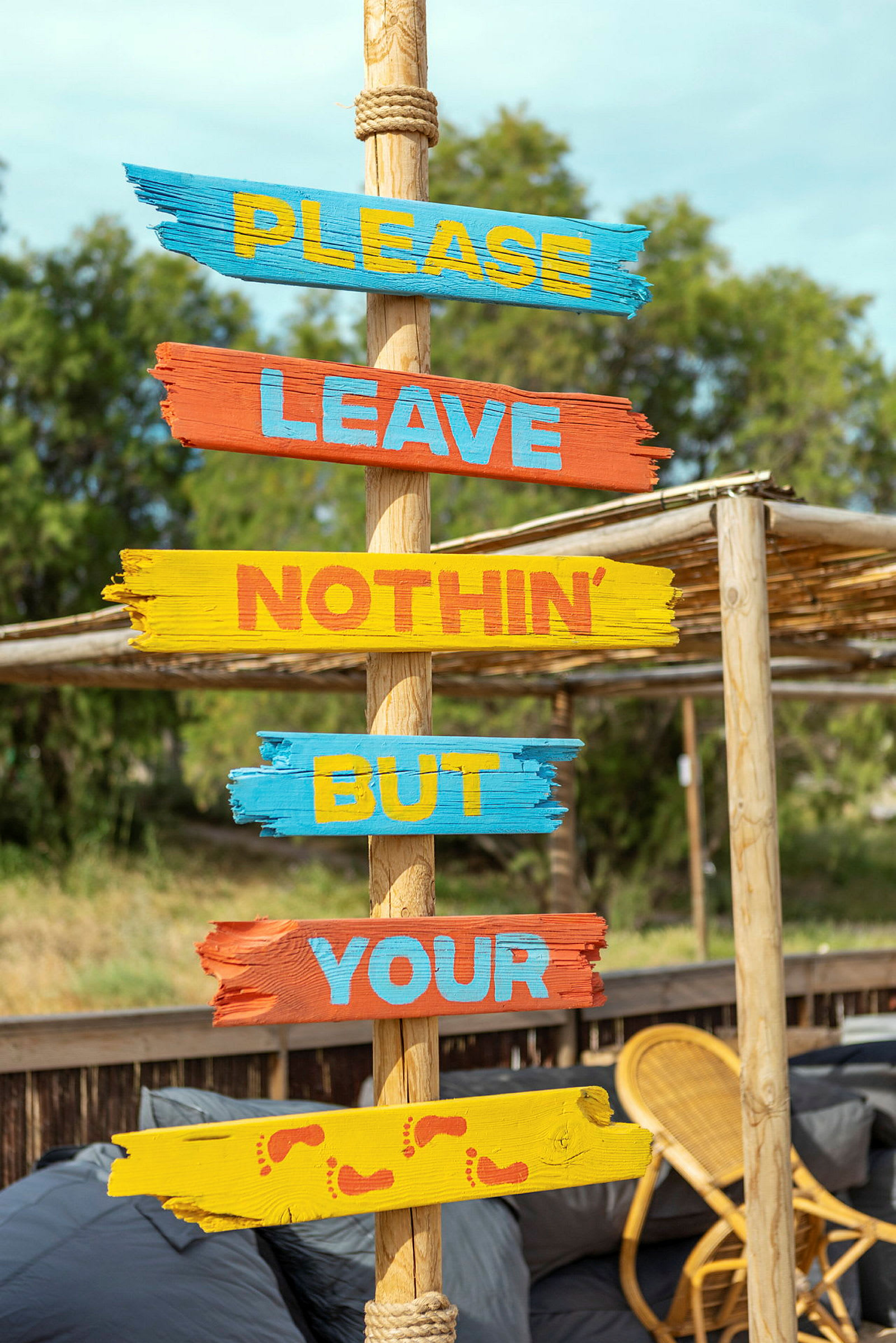Skilt med teksten 'Please leave nothin’ but your', malt på fargerike treplanker. (AI-generert tekst)