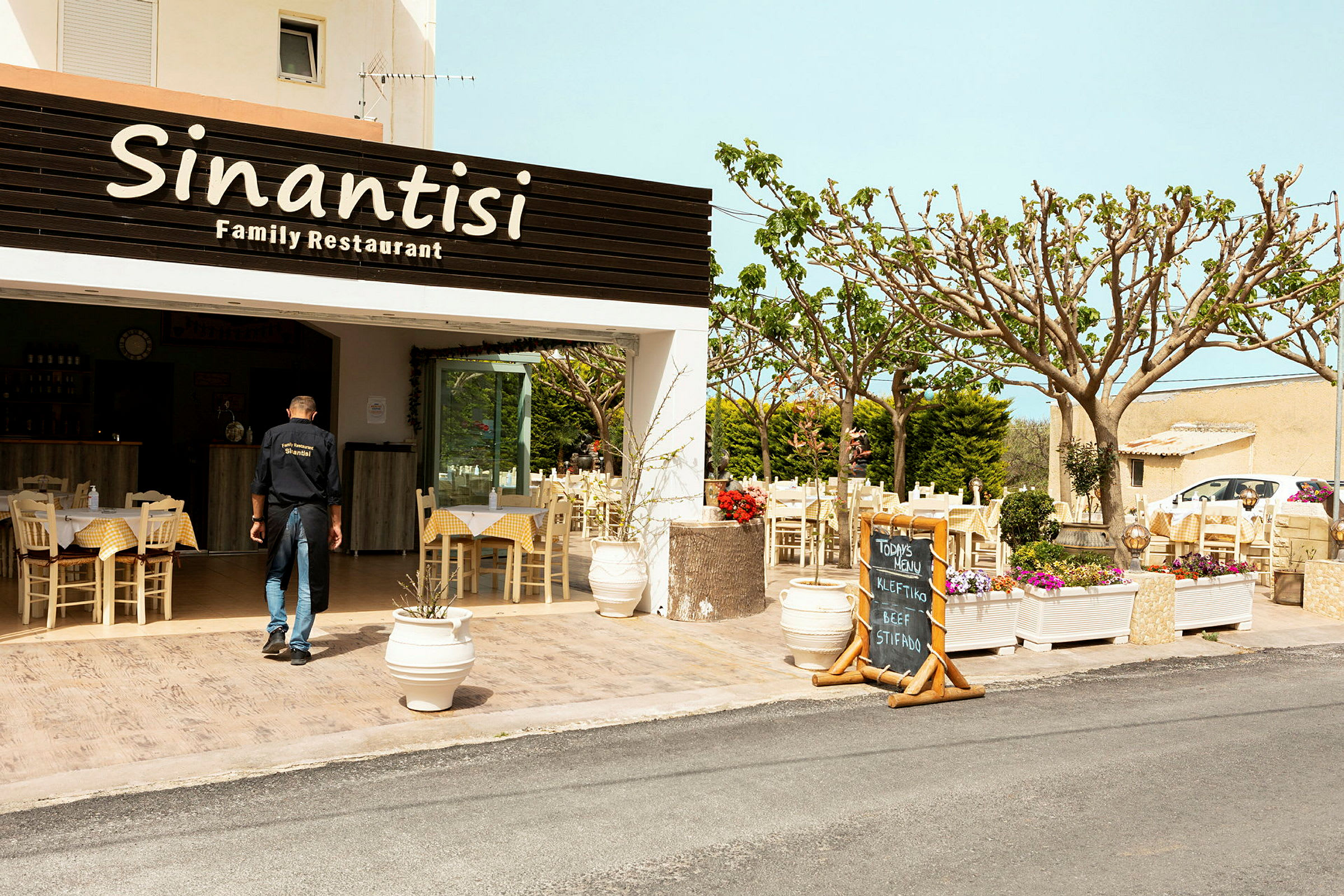 Restauranten Sinantisi med uteservering dekorert med blomster. (AI-generert tekst)