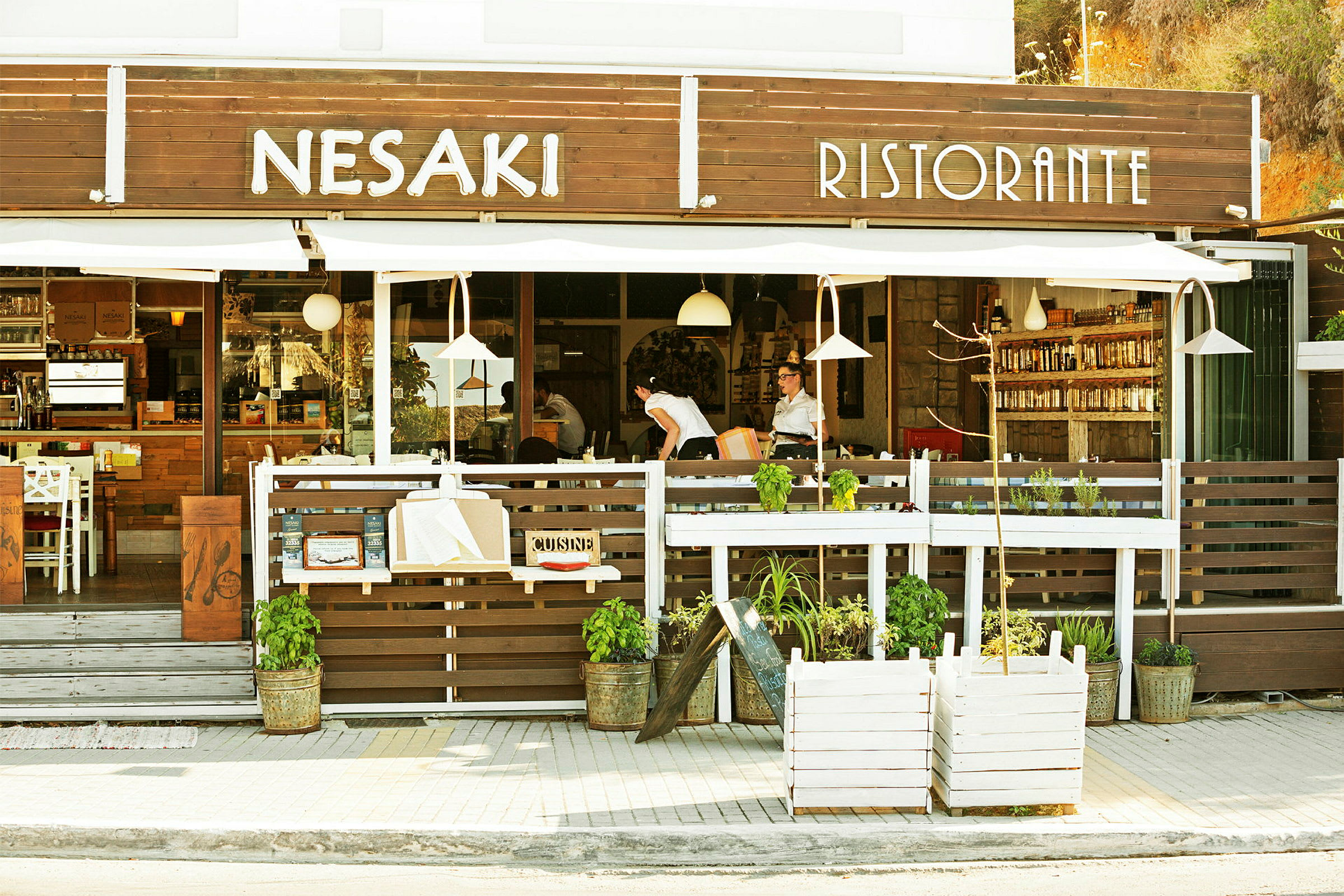 Bilde av fasaden til en restaurant med teksten "Nesaki Ristorante" over inngangen og med uteservering. (AI-generert tekst)