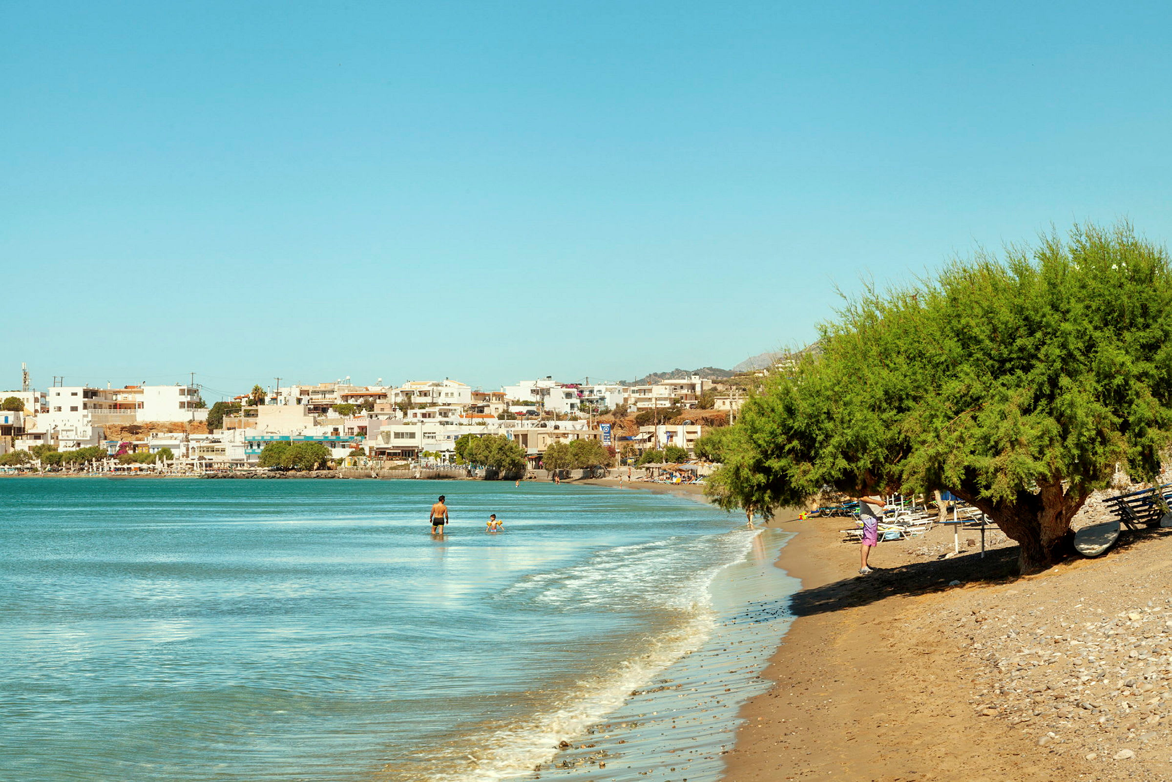 En kystlinje med strand, hav og bygninger i bakgrunnen. (AI-generert tekst)
