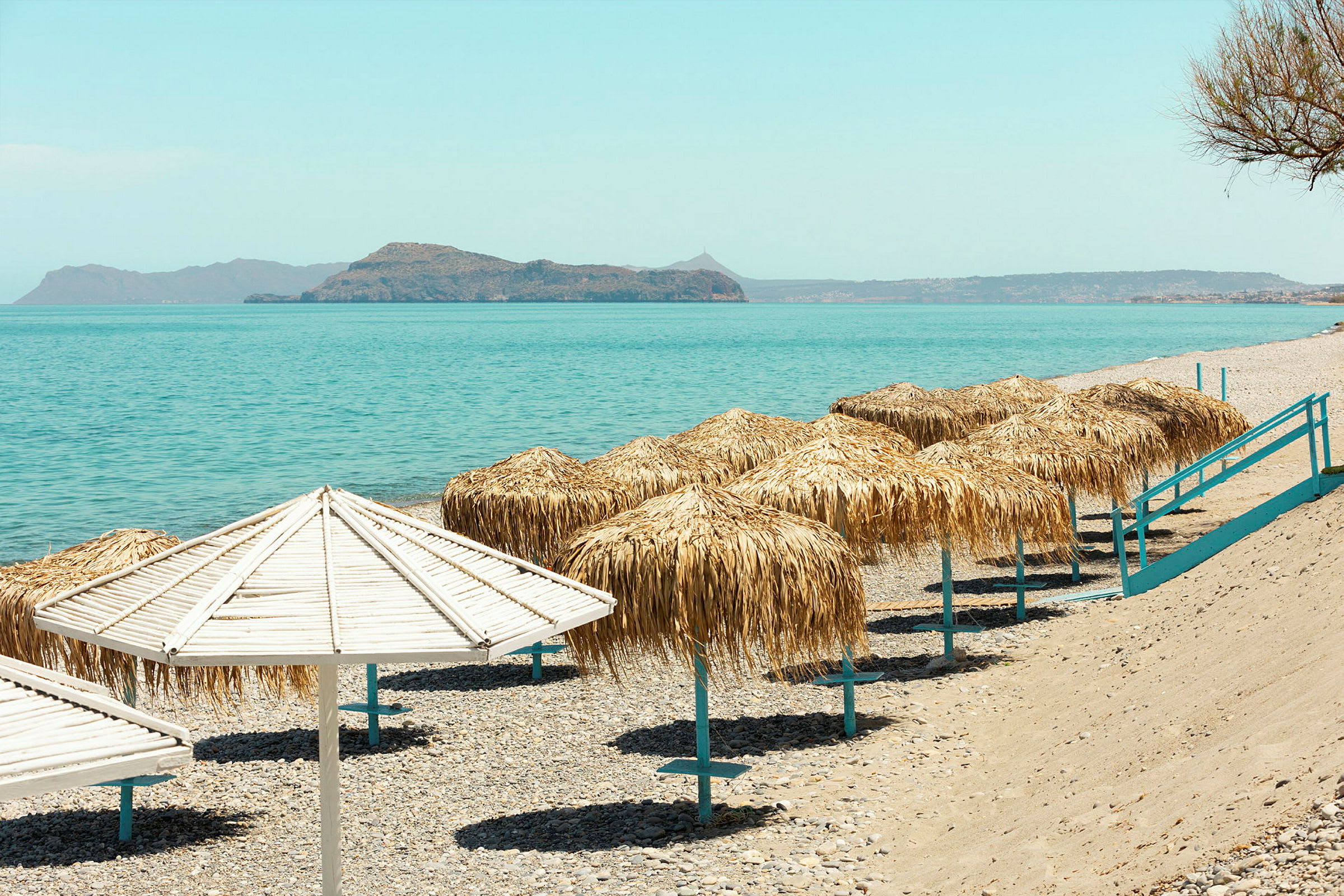 Strand med parasoller og hav i bakgrunnen. (AI-generert tekst)