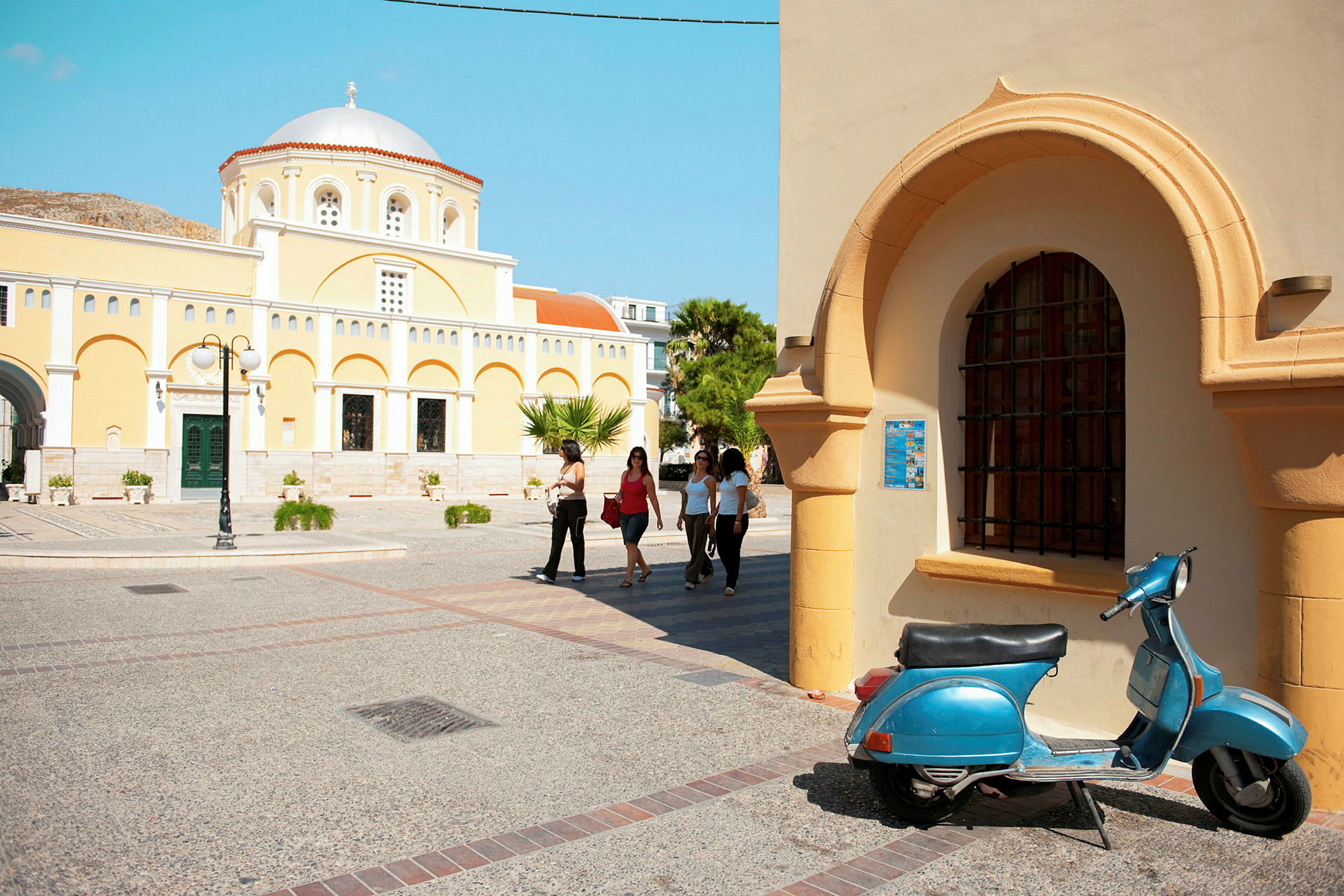 Gul kirkelig bygning med kuppeltak, arkitektoniske detaljer og en blå scooter i forgrunnen. (AI-generert tekst)