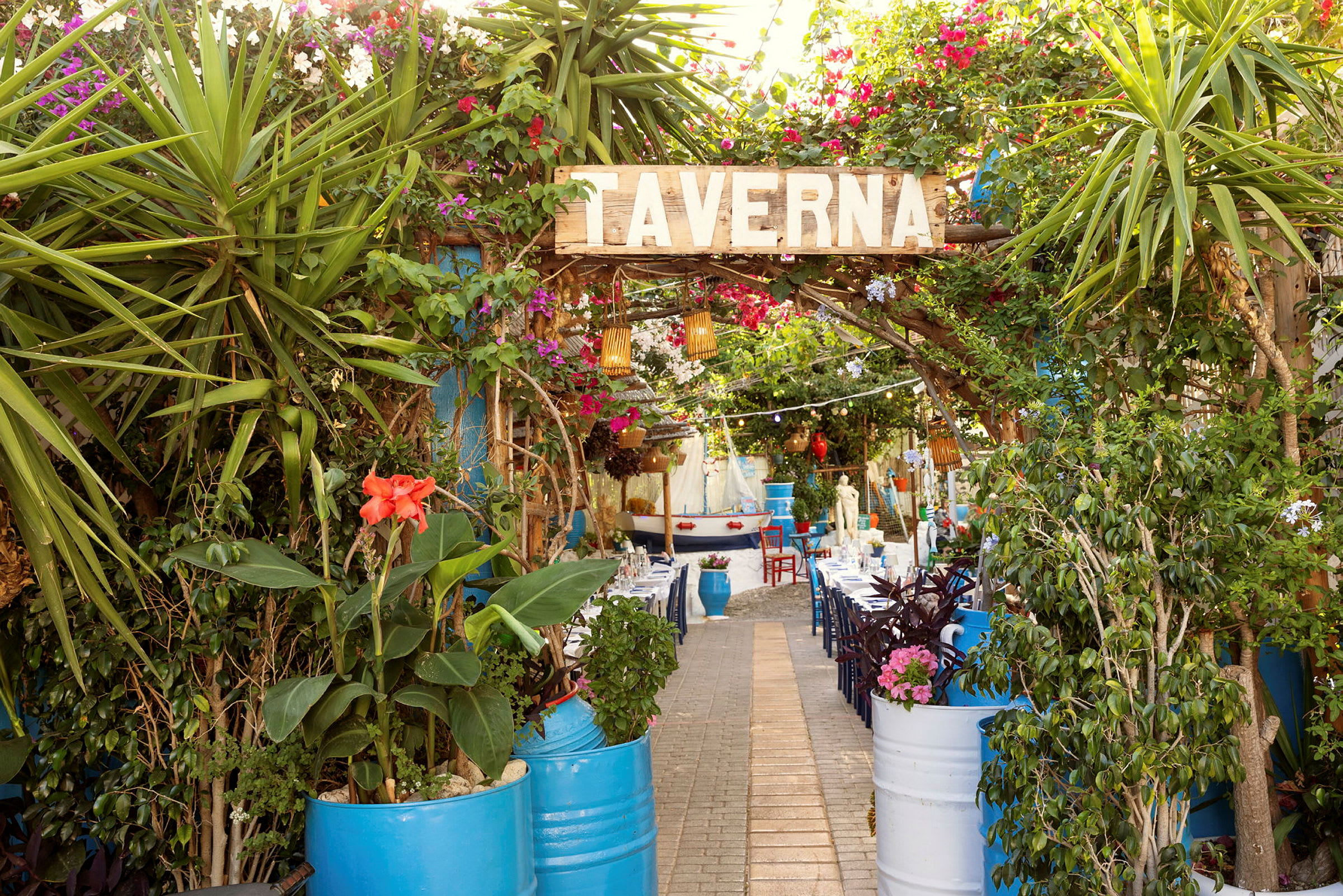 Inngangen til en taverna med grønt og fargerike blomster. (AI-generert tekst)