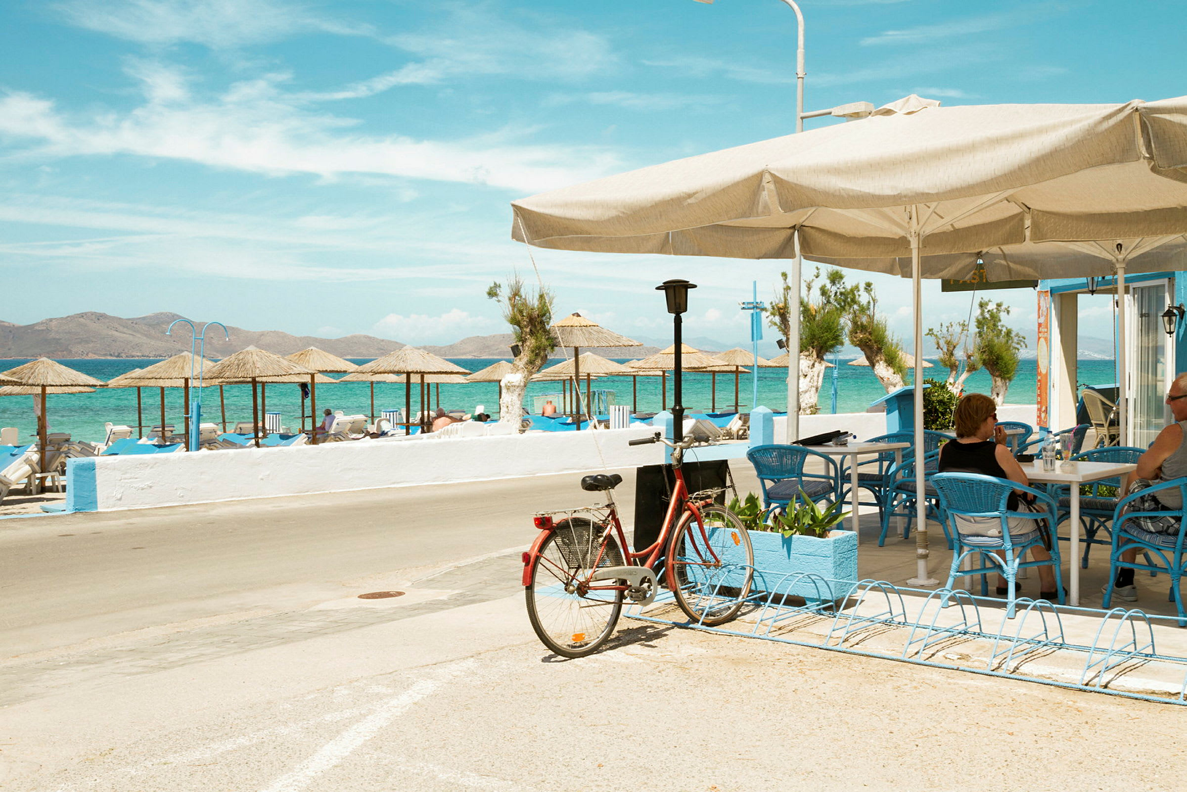 Sykkel parkert ved et kafé med utsikt over stranden og havet. (AI-generert tekst)