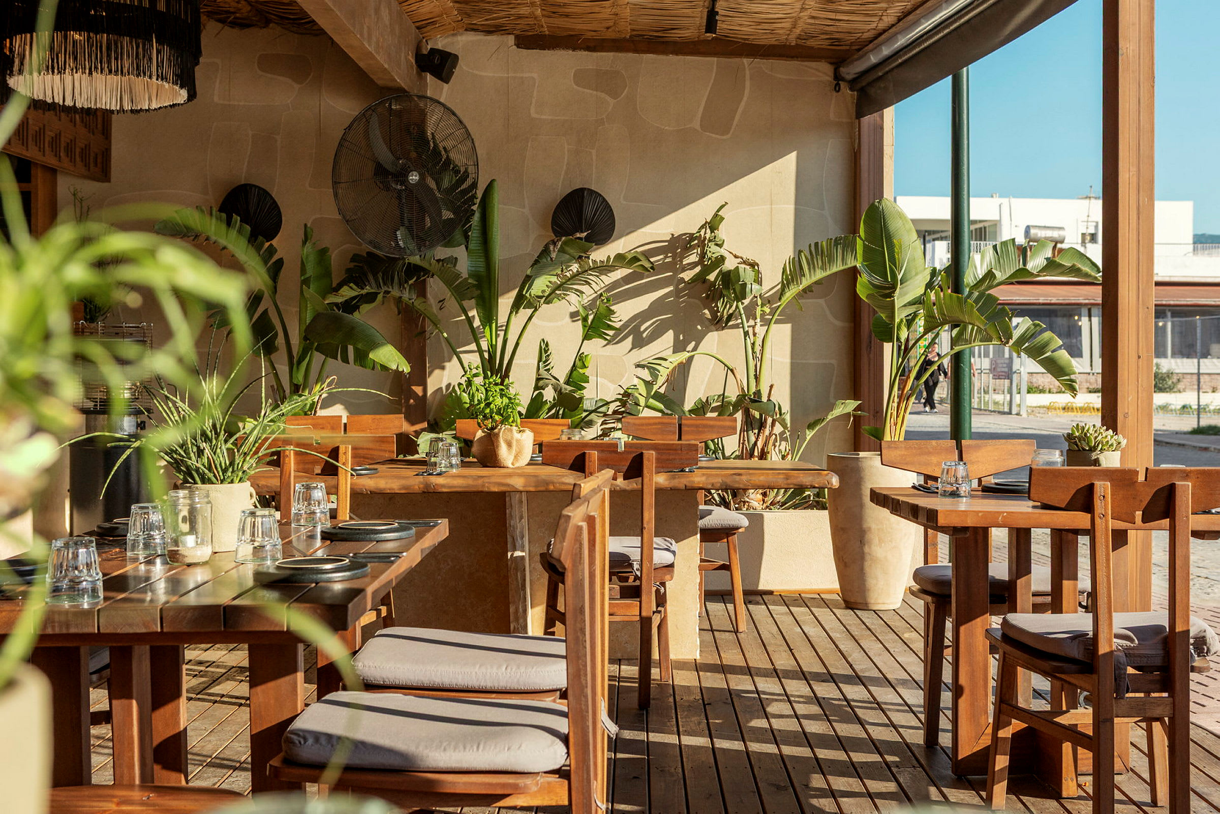 En utendørsrestaurant med tremøbler og grønne planter. (AI-generert tekst)