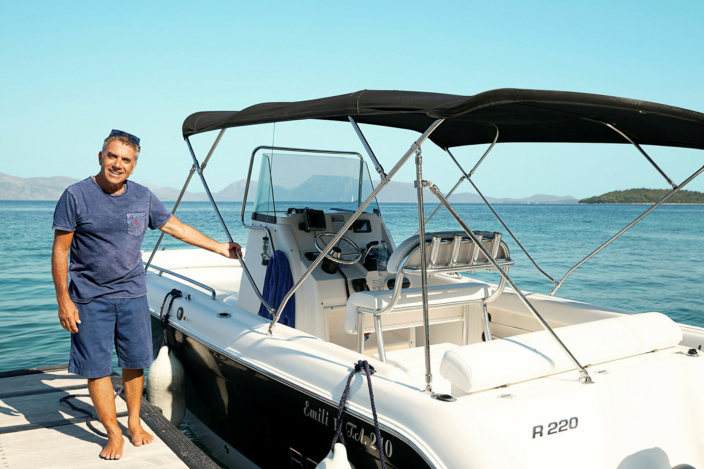 En motorbåt med to seter står ved en brygge nær havet. (AI-generert tekst)