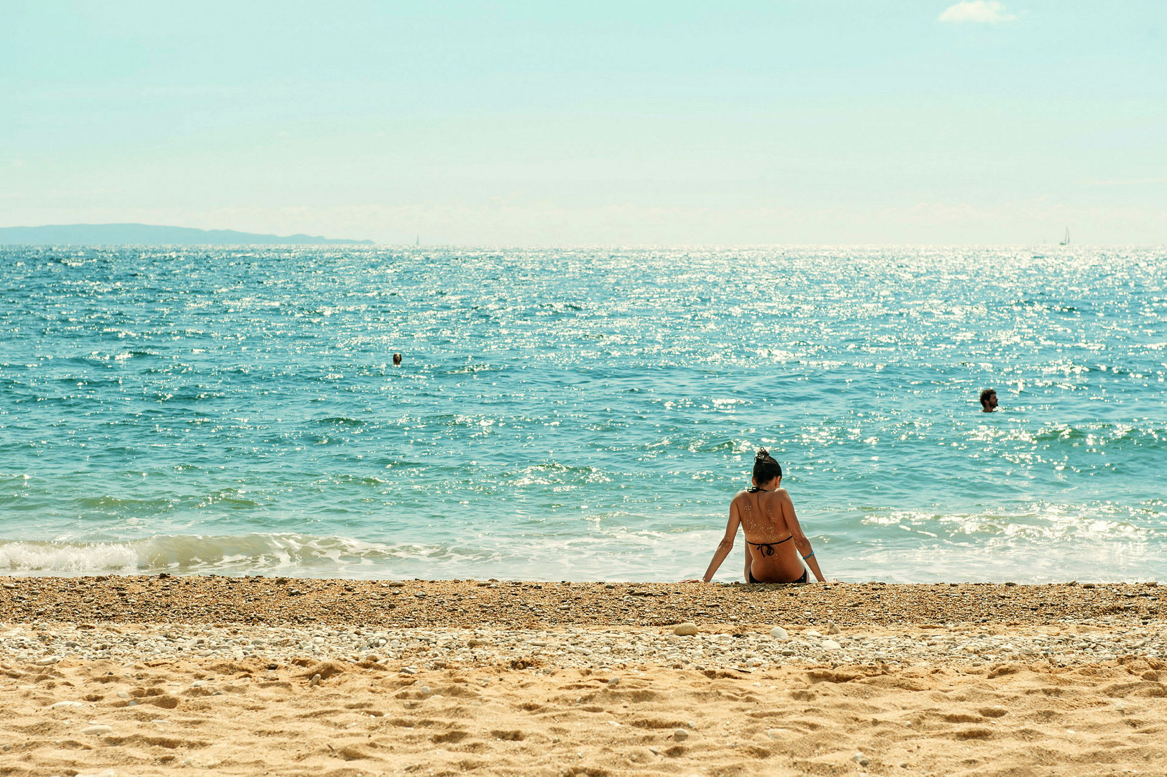 En person sitter på stranden med havet i bakgrunnen. (AI-generert tekst)