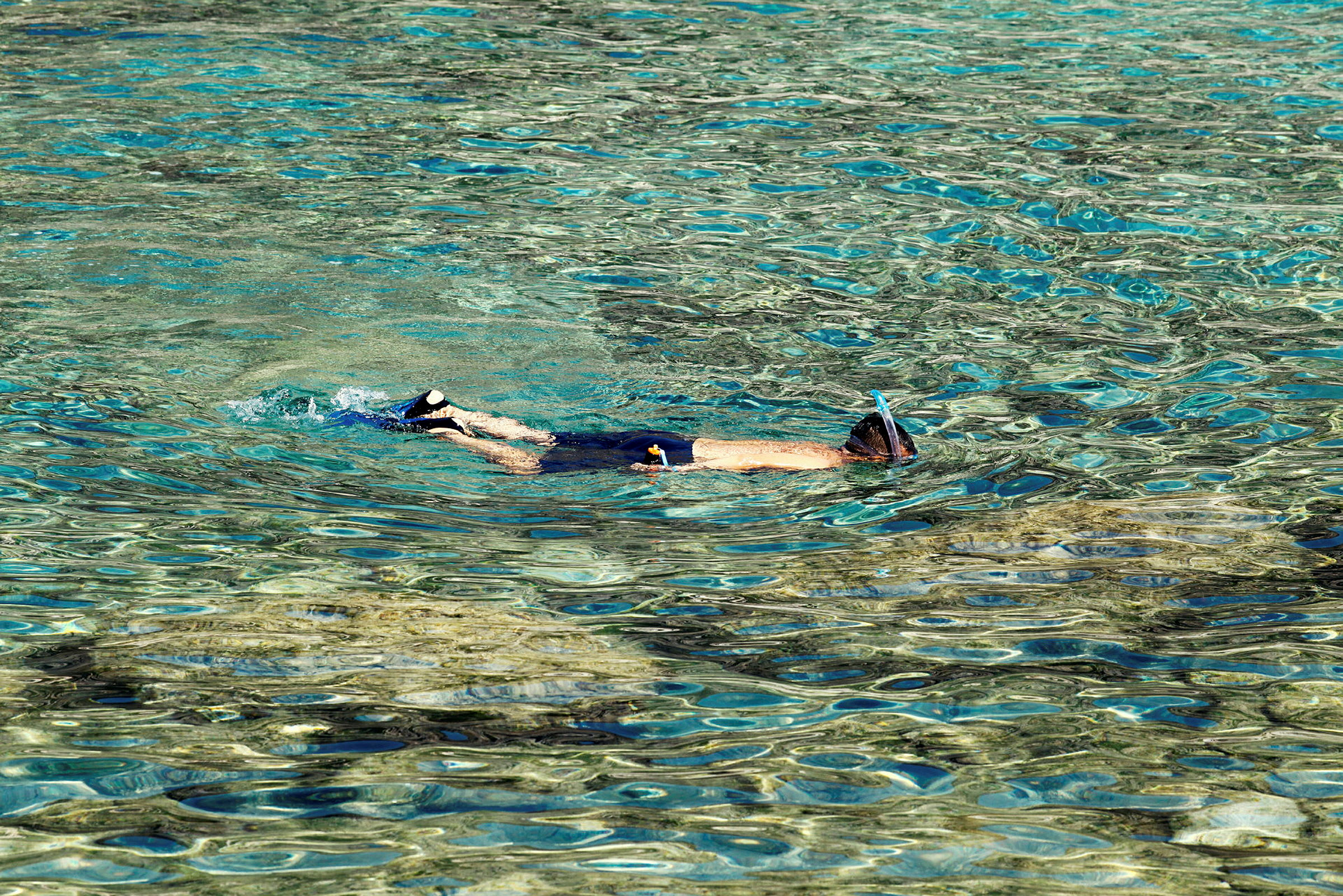 Person med snorkel svømmer i klart vann. (AI-generert tekst)