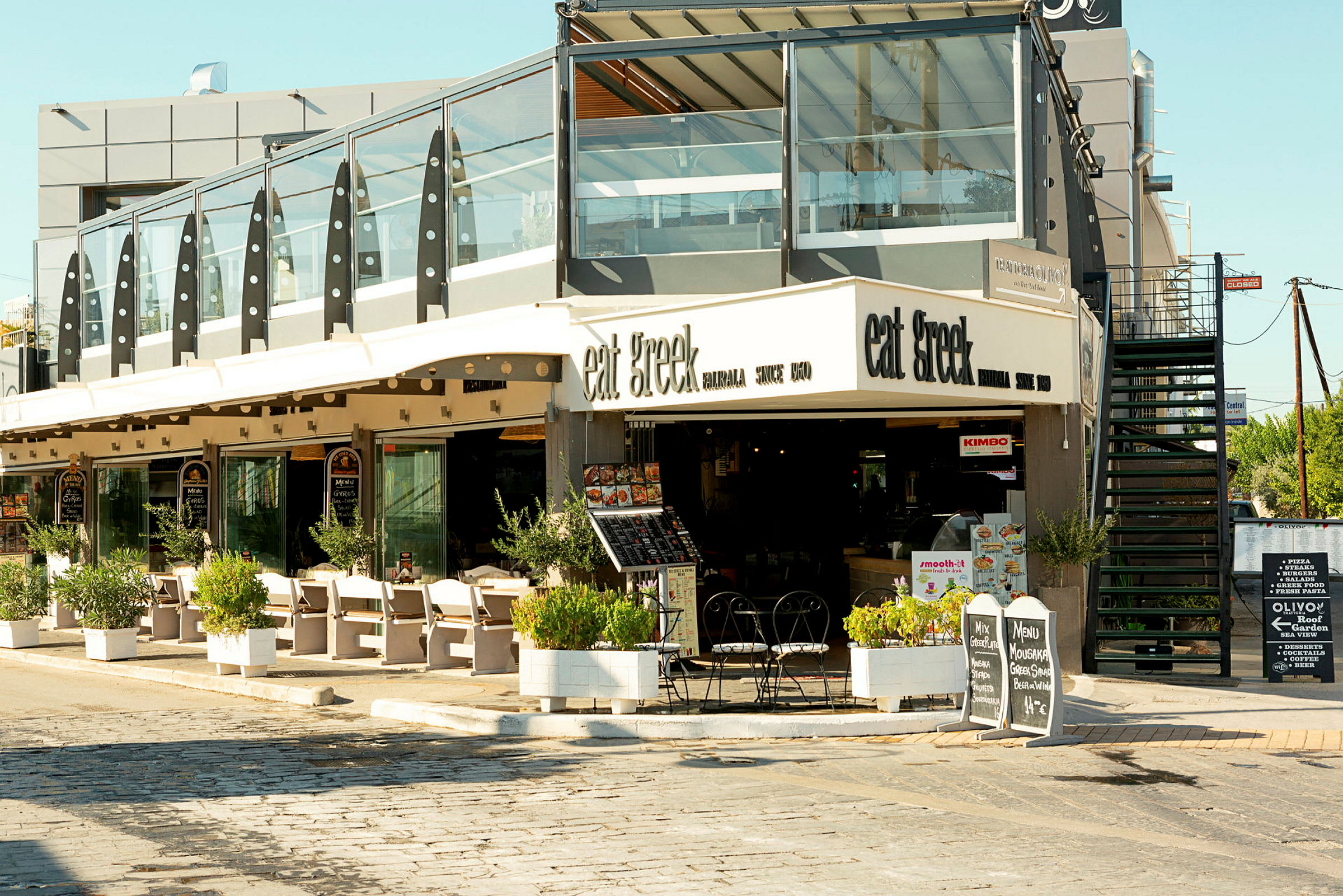 Restaurant med uteservering og skilt som viser menyen. (AI-generert tekst)