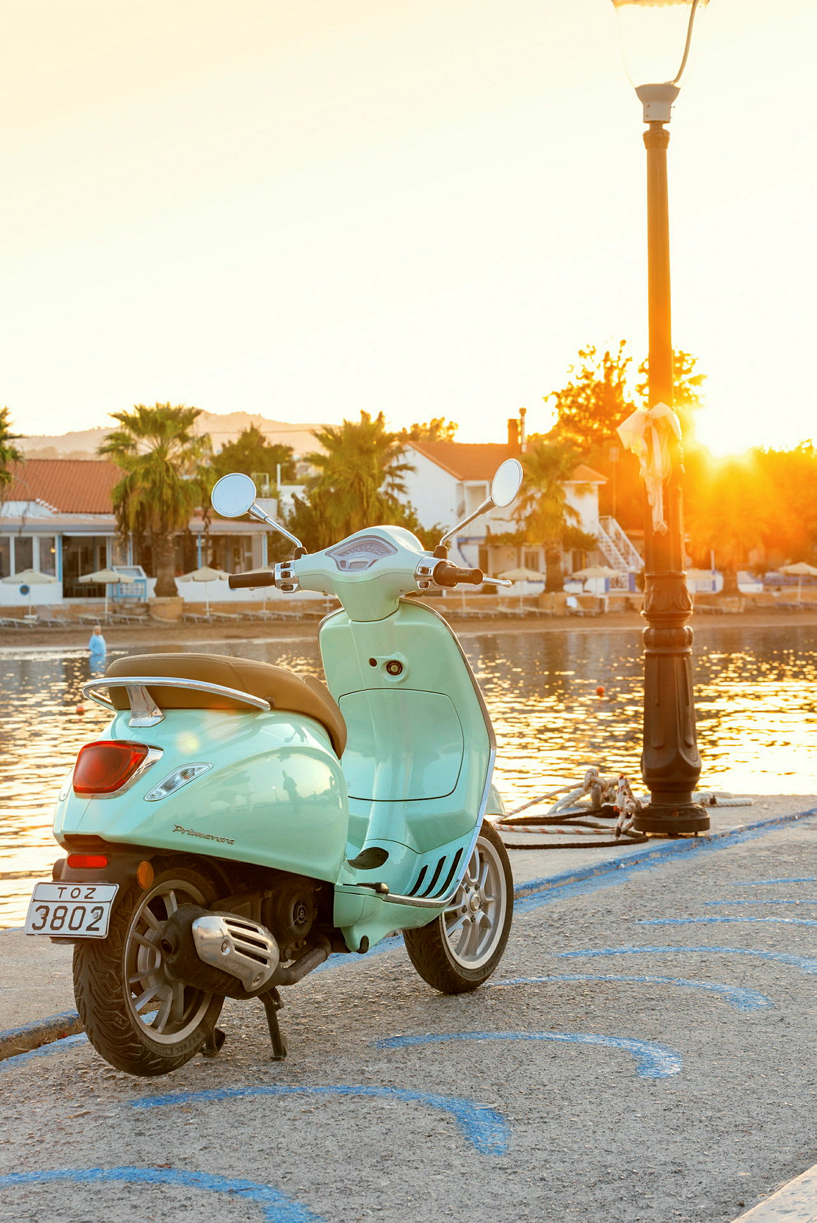 En lysegrønn scooter ved en kai på kvelden med solnedgangen. (AI-generert tekst)