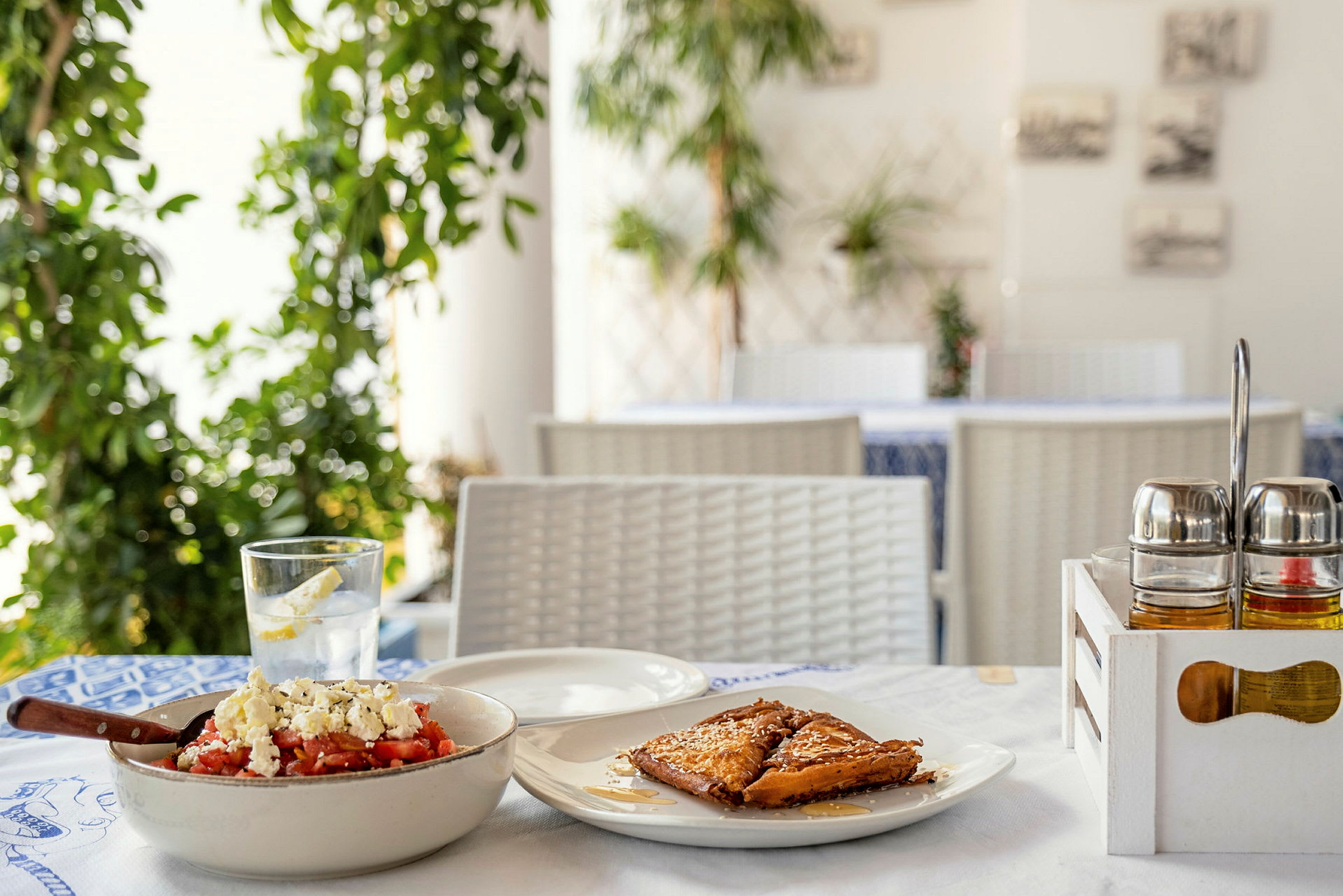 En nærbilde av et restaurantbord med en tradisjonell gresk rett og dessert. (AI-generert tekst)