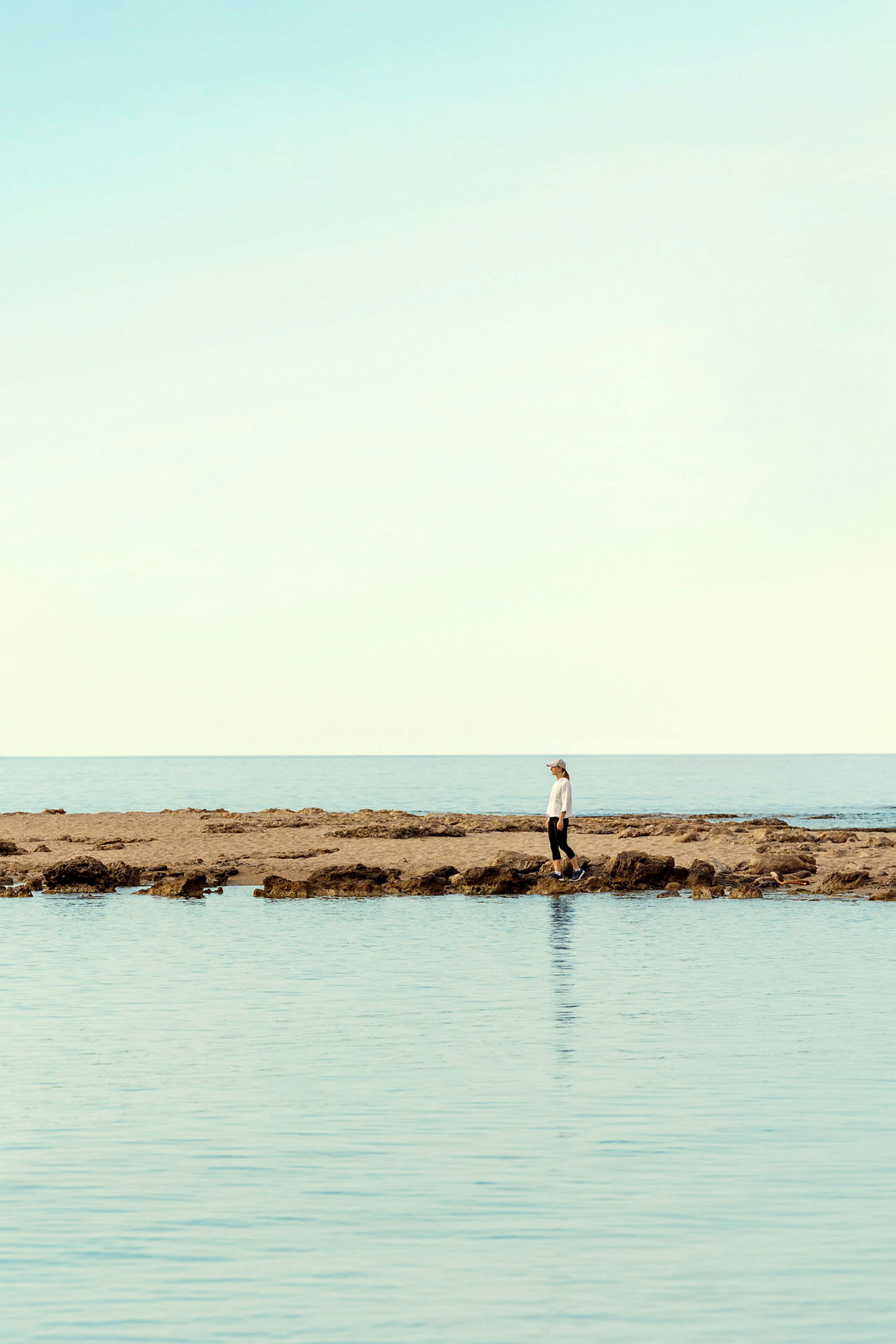 Person står på steinete strand ved sjøen. (AI-generert tekst)