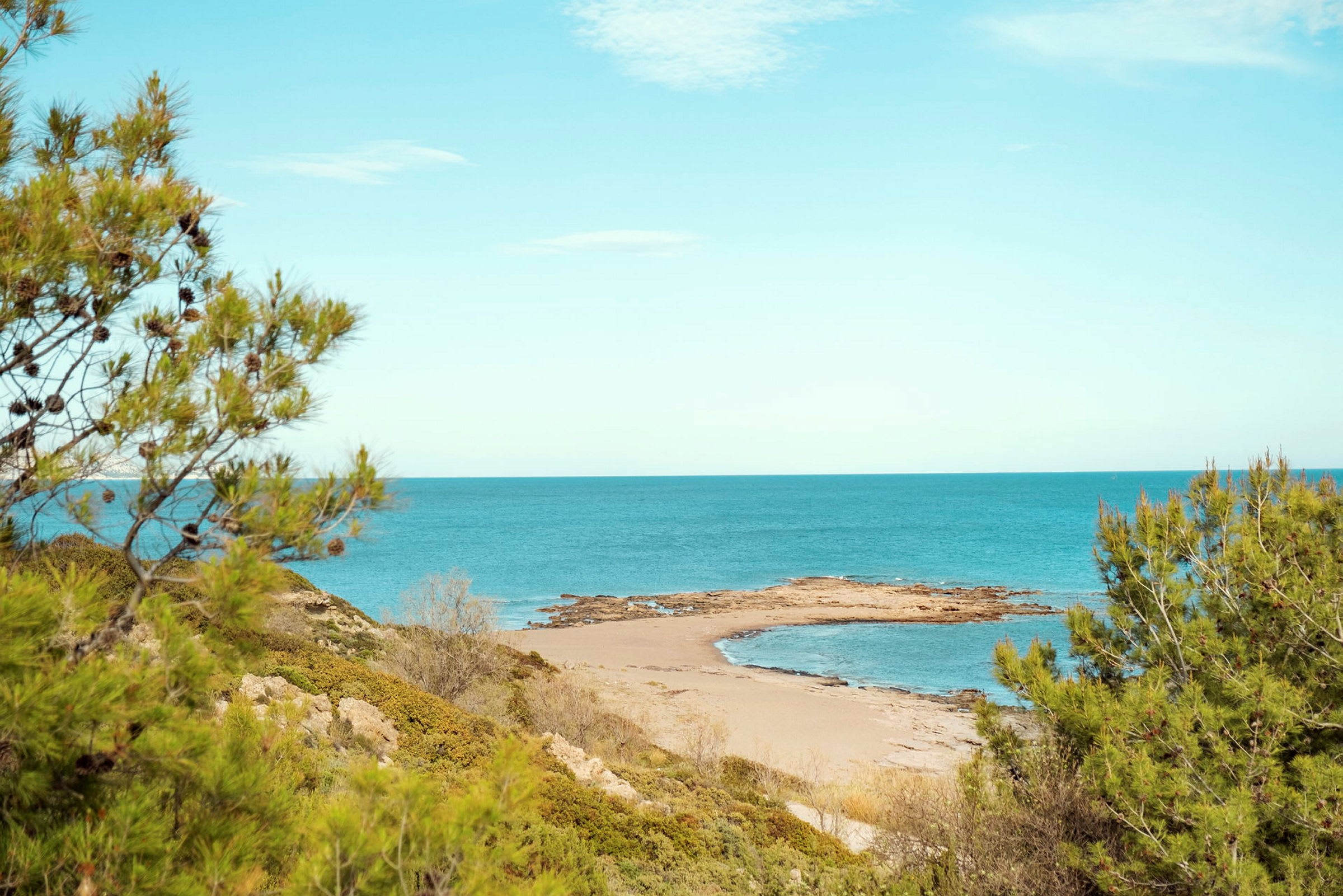 En avsides sandstrand med omkringliggende vegetasjon og havet i bakgrunnen. (AI-generert tekst)