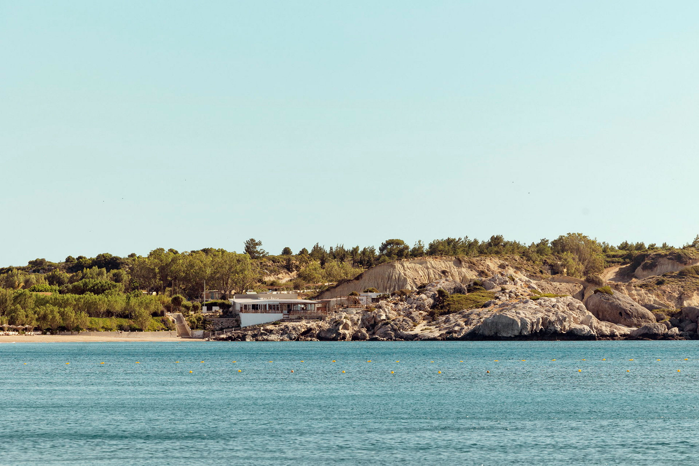 En strand og et hav med en bygning ved en steinete kyst. (AI-generert tekst)