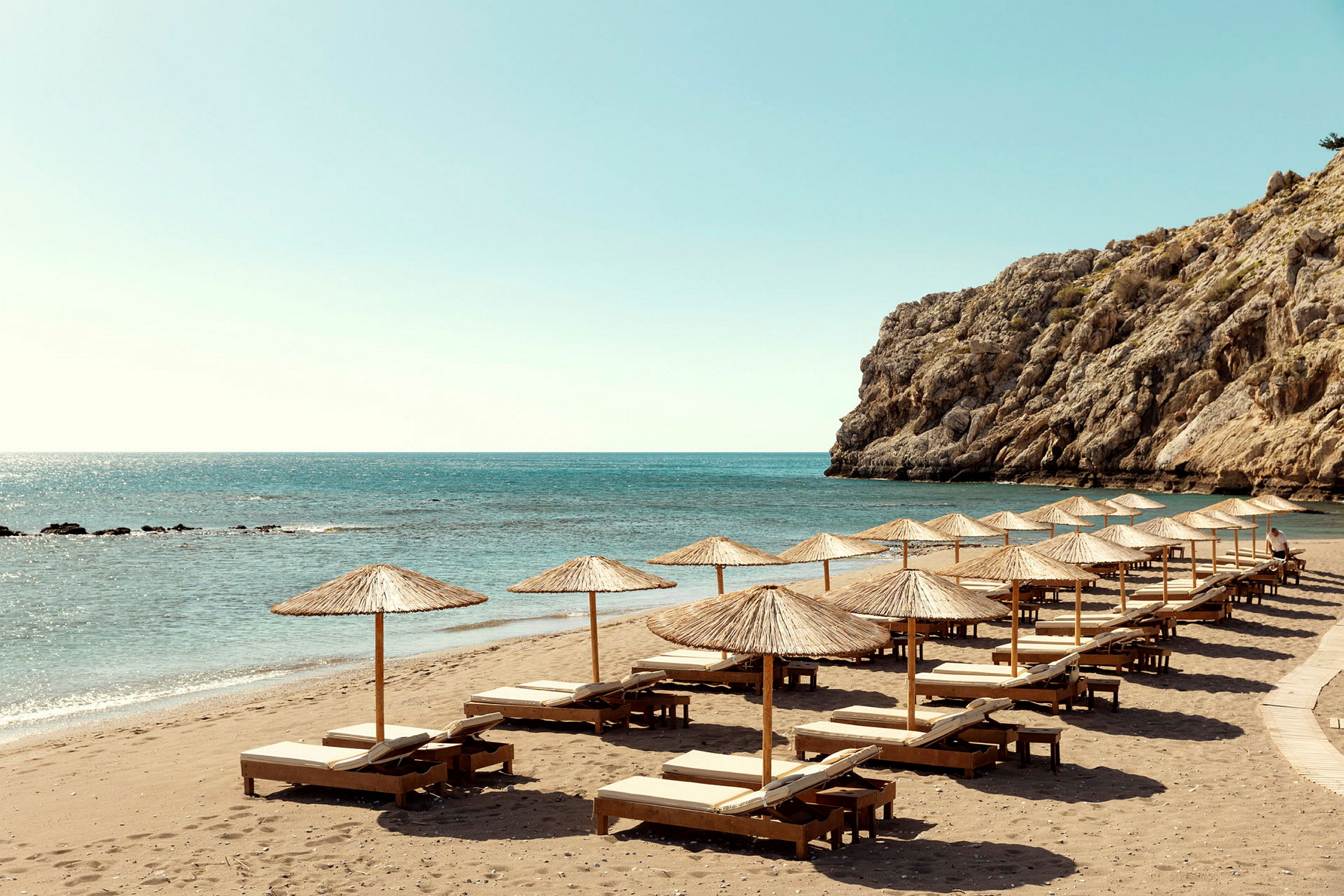 Strand med solsenger og parasoller ved havet. (AI-generert tekst)