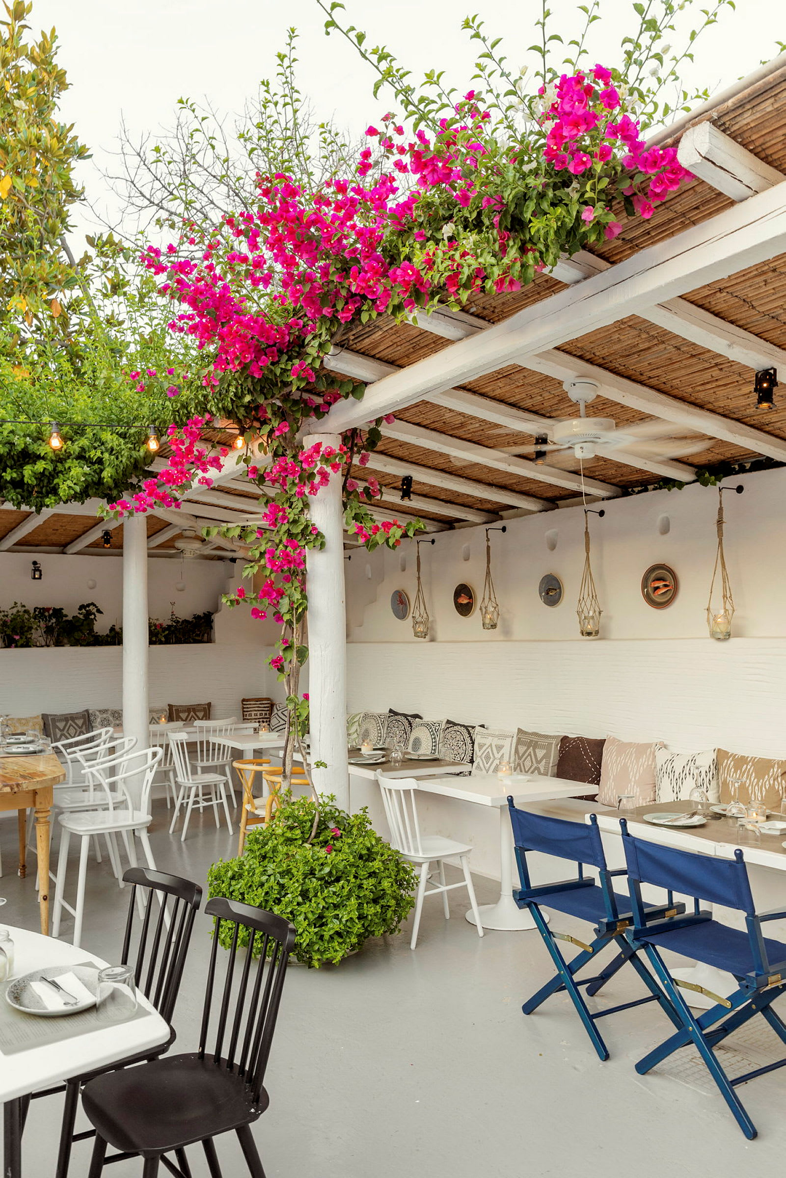 En terrasse med sitteplasser, fargerike blomster og hengende dekorasjoner. (AI-generert tekst)