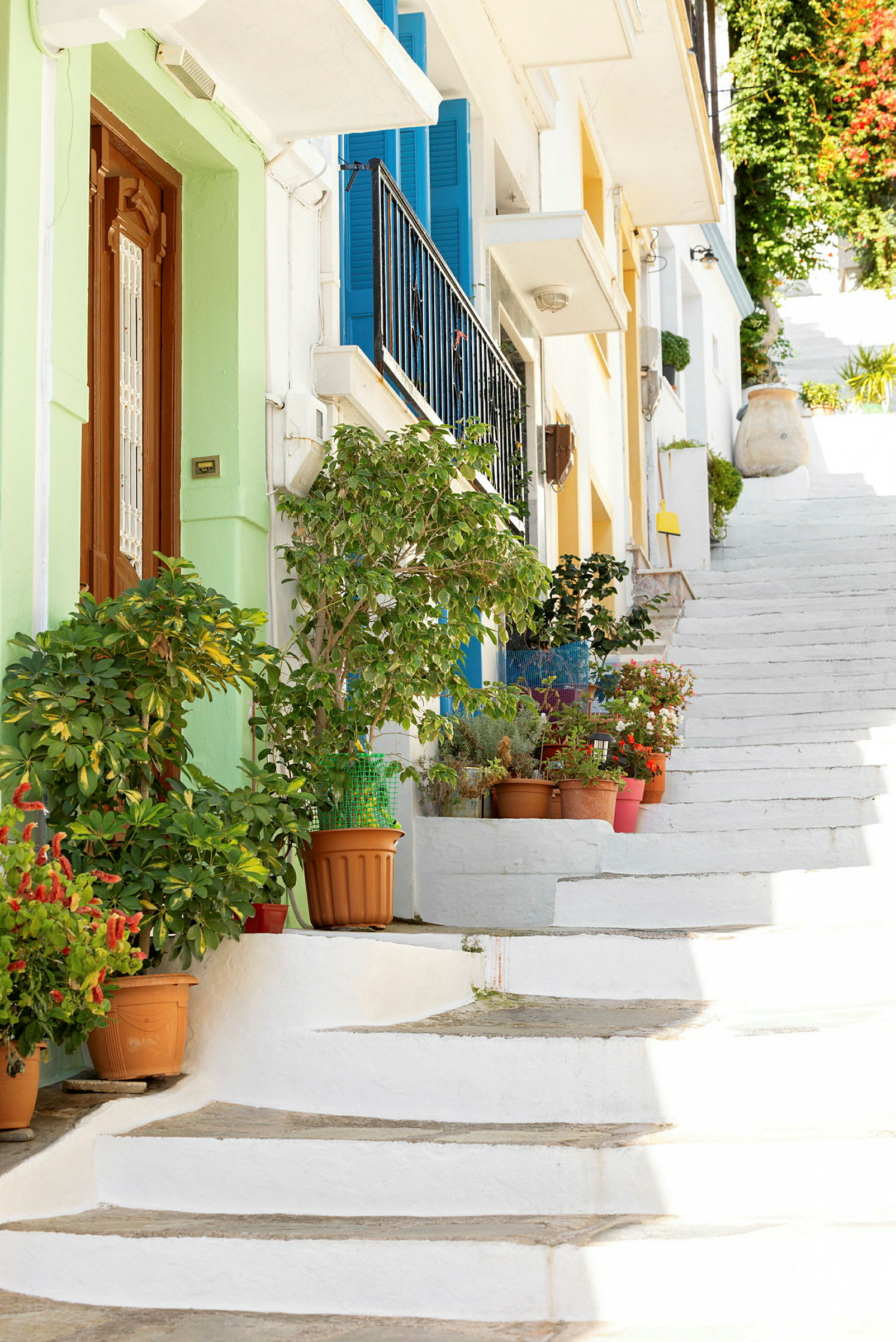Hvite trapper omgitt av fargerike hus og blomsterpotter. (AI-generert tekst)