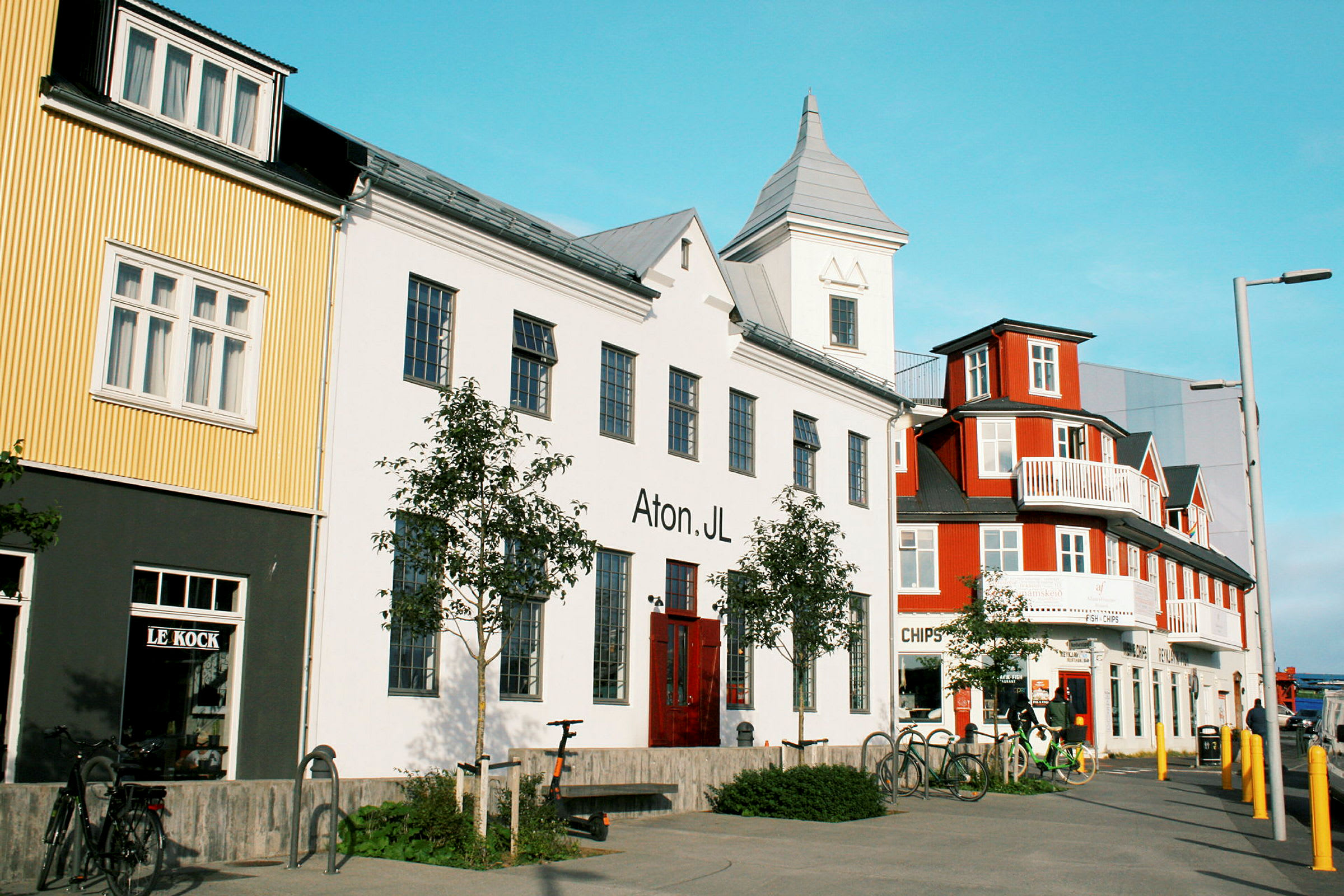 Flere fargerike bygninger langs en gate med sykler parkert foran. (AI-generert tekst)