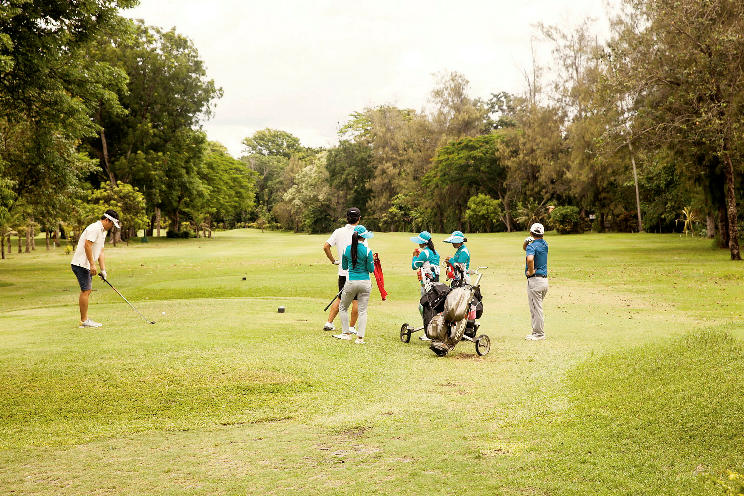 En gruppe mennesker på en grønn golfbane, noen holder golfklubber. (AI-generert tekst)