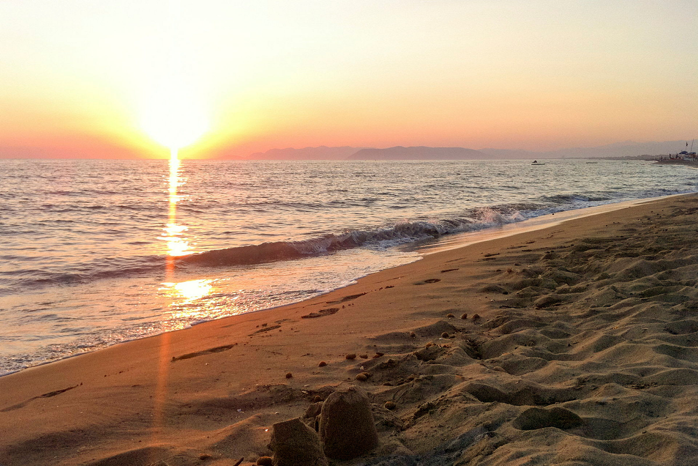 Solnedgang over havet ved en sandstrand. (AI-generert tekst)