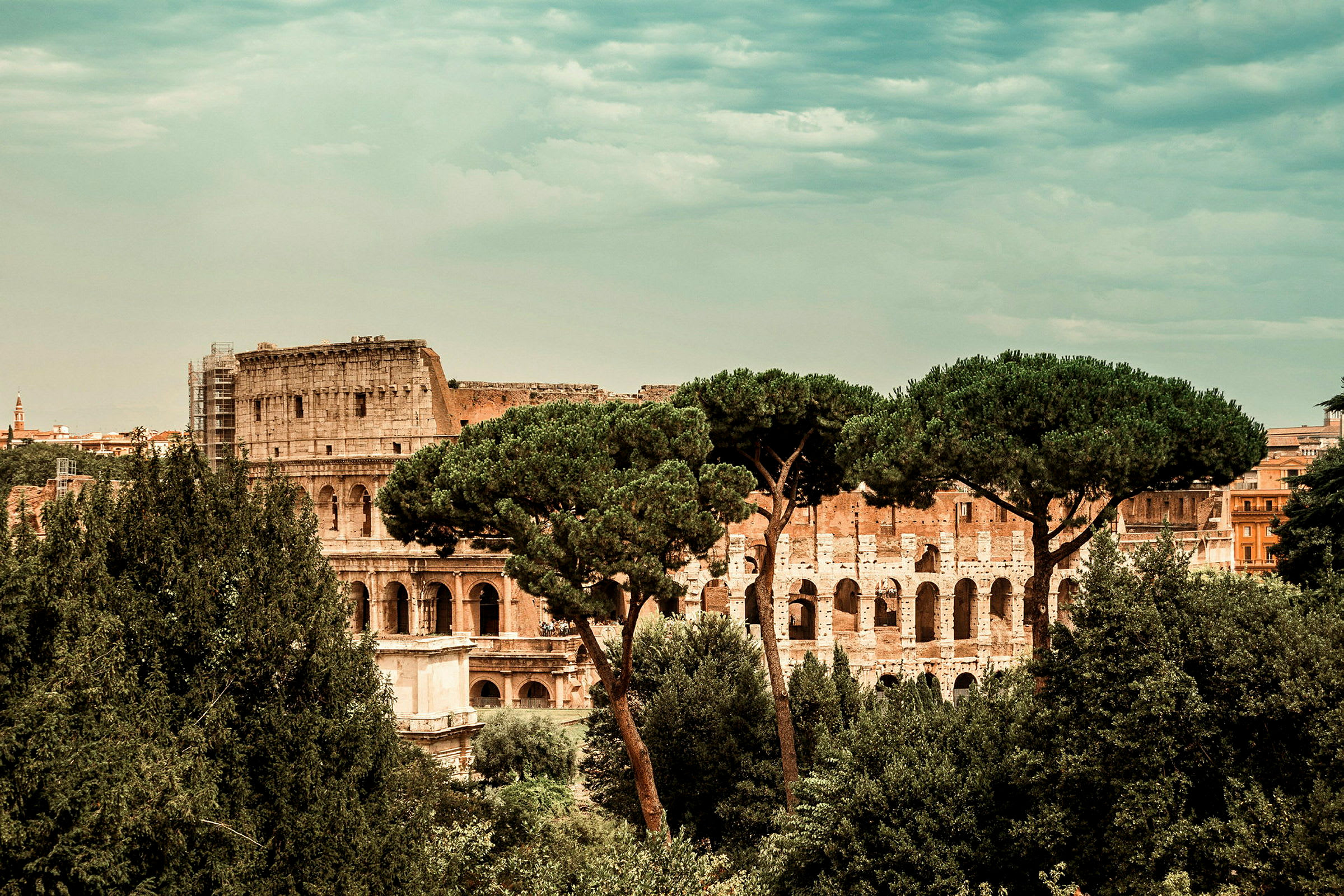 Utsikt over Colosseum i Roma, omgitt av trær. (AI-generert tekst)