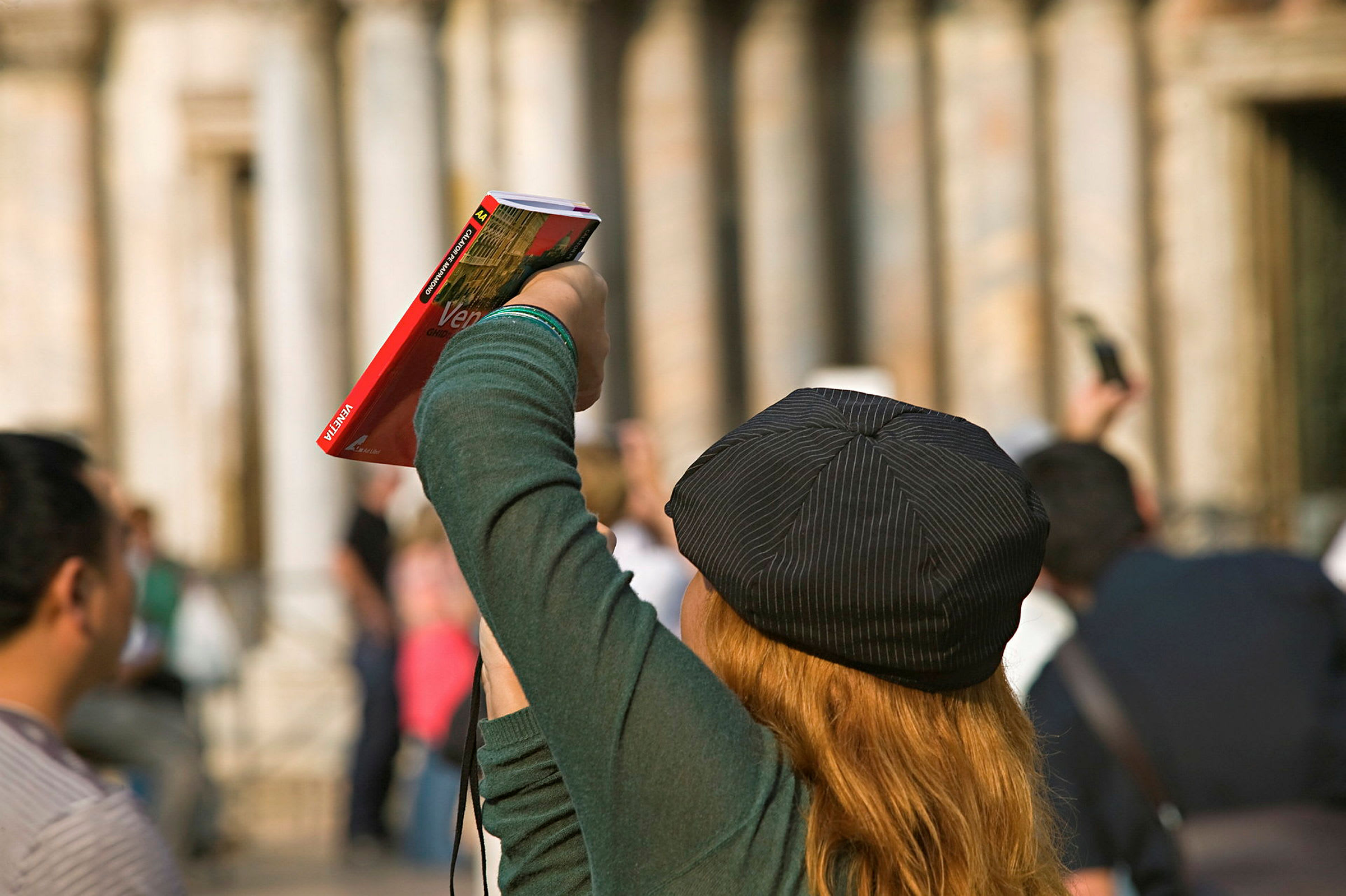 En person med hatt holder opp en reiseguide i en gruppe mennesker. (AI-generert tekst)