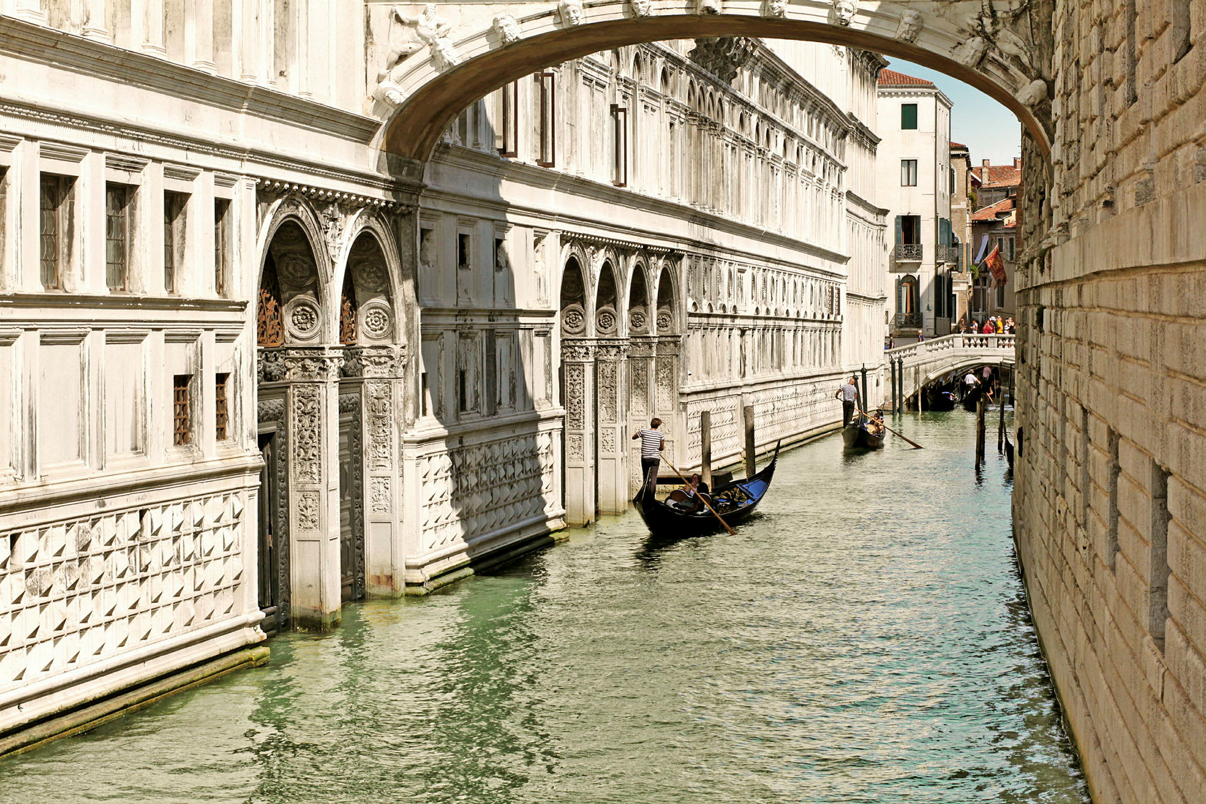 En gondol flytter seg langs en kanal i Venezia, omgitt av historiske bygninger og en liten bro. (AI-generert tekst)