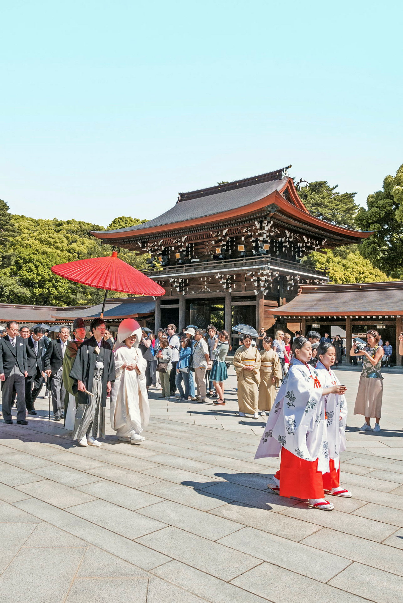 En tradisjonell seremoni ved en japansk helligdom, med mennesker i tradisjonelle klær og en bygning med rødt tak i bakgrunnen. (AI-generert tekst)