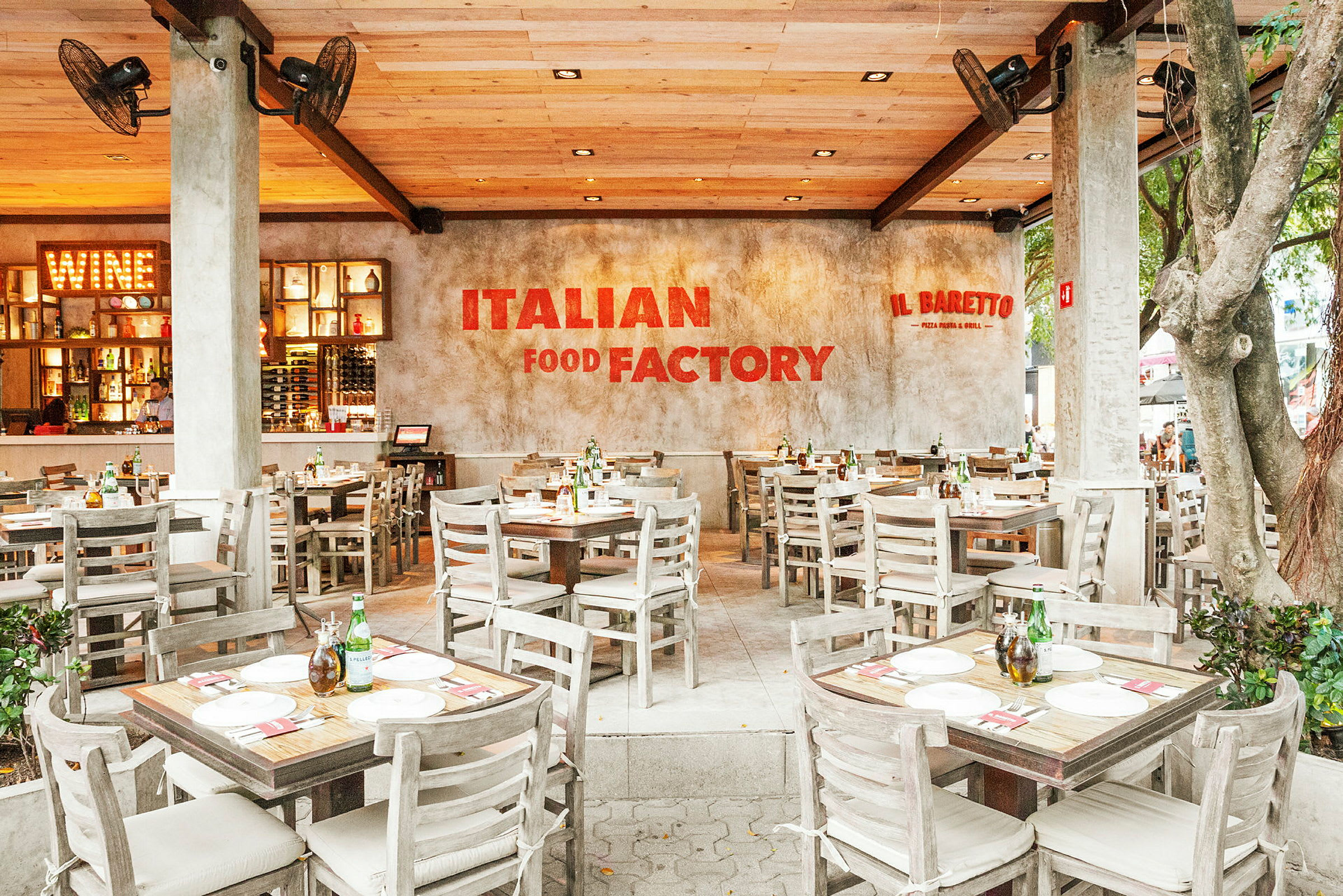 En italiensk restaurant med trebord og stoler, en innbydende atmosfære og et skilt med teksten "Italian Food Factory" på veggen. (AI-generert tekst)