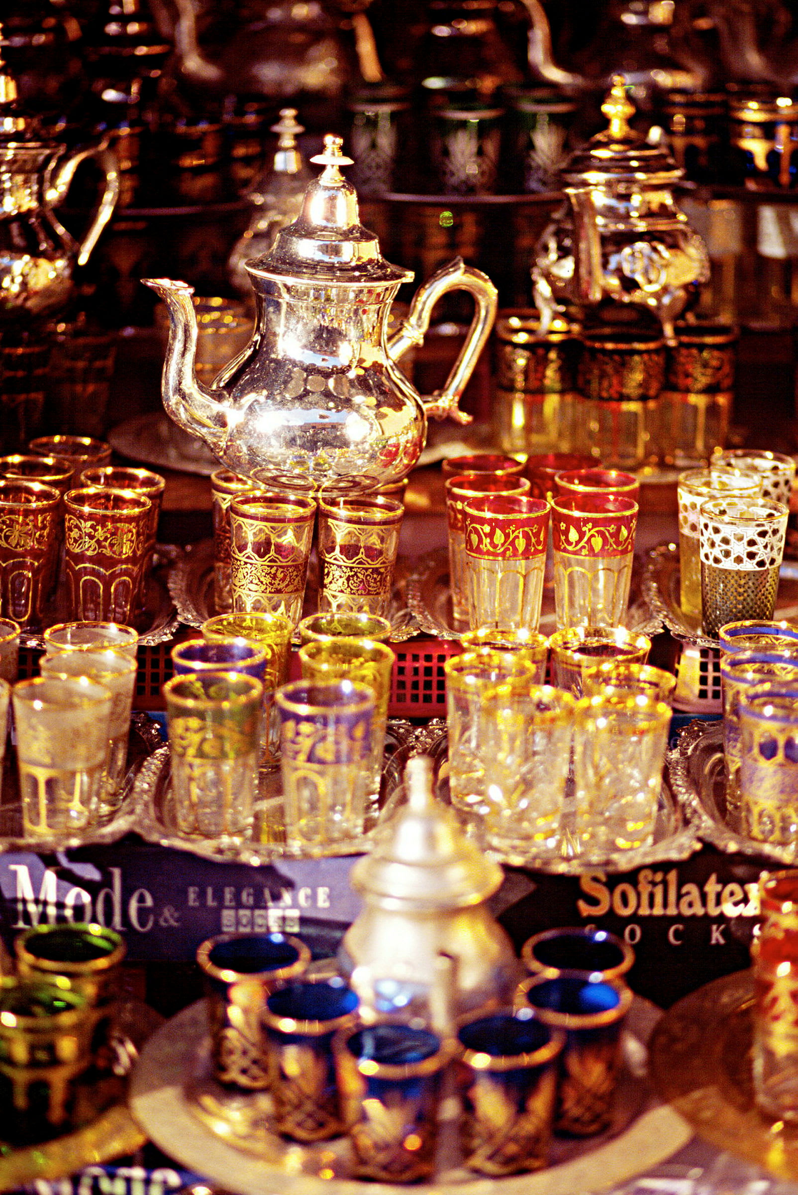 En samling dekorative tekanner og fargerike glass med detaljerte ornamenter. (AI-generert tekst)