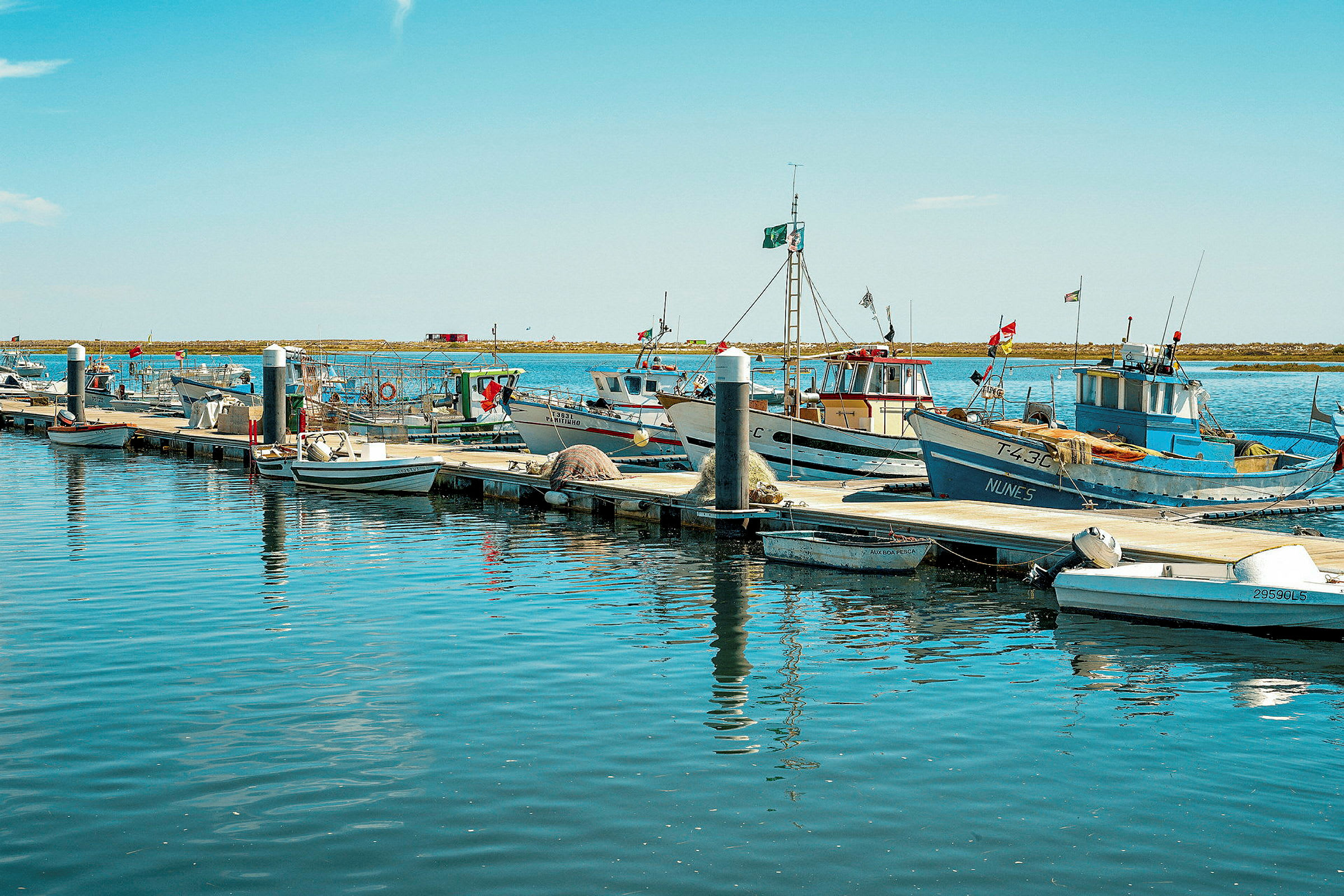 Fiskebåter fortøyd ved kaien i en havn. (AI-generert tekst)