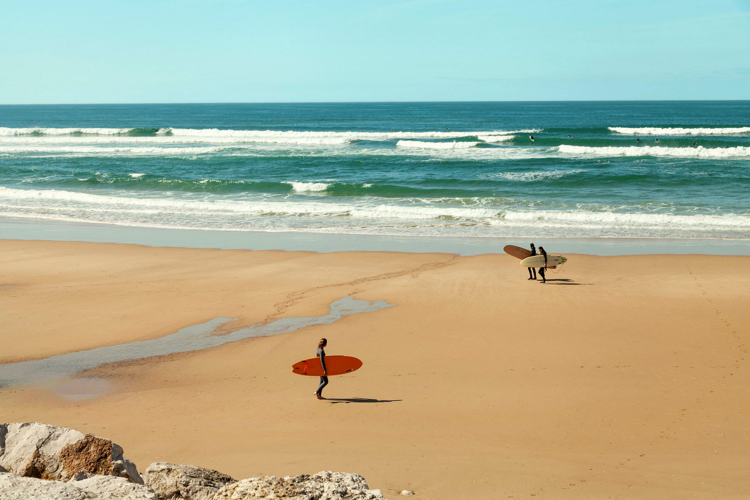 Surfere på en sandstrand med bølger i bakgrunnen. (AI-generert tekst)
