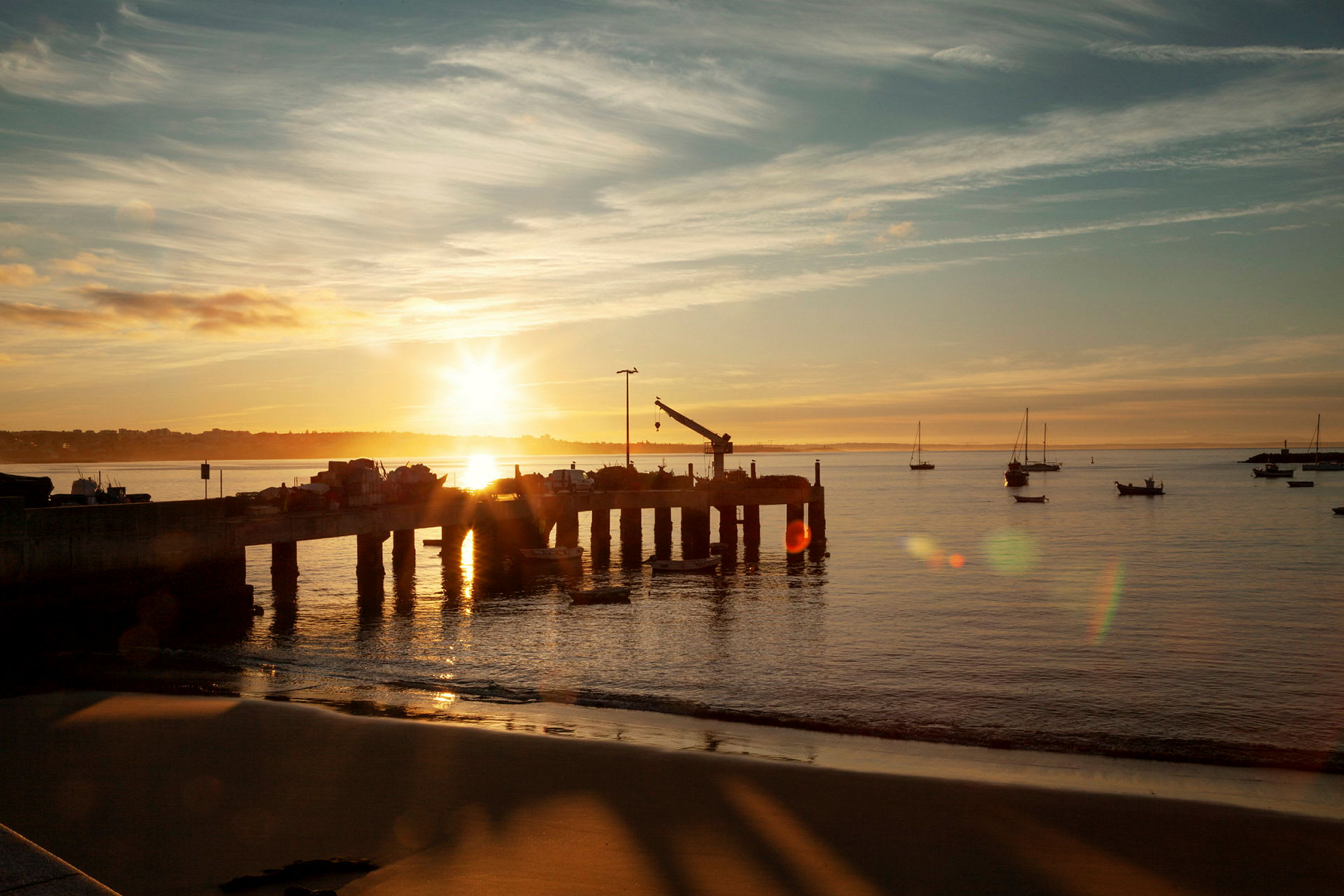 En brygge med småbåter i solnedgang. (AI-generert tekst)