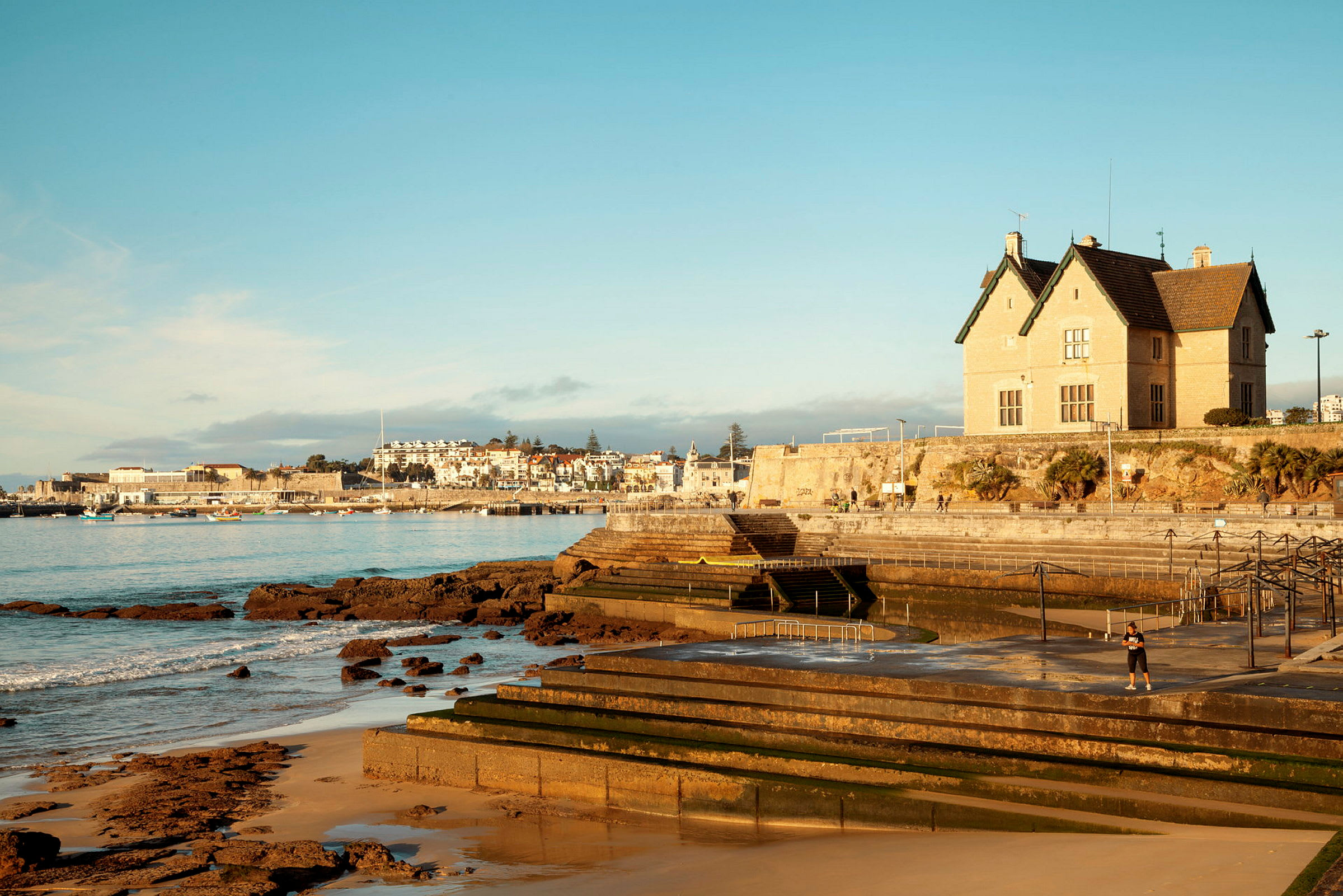 En kystby med en bygning ved vannet og steinete strand. (AI-generert tekst)