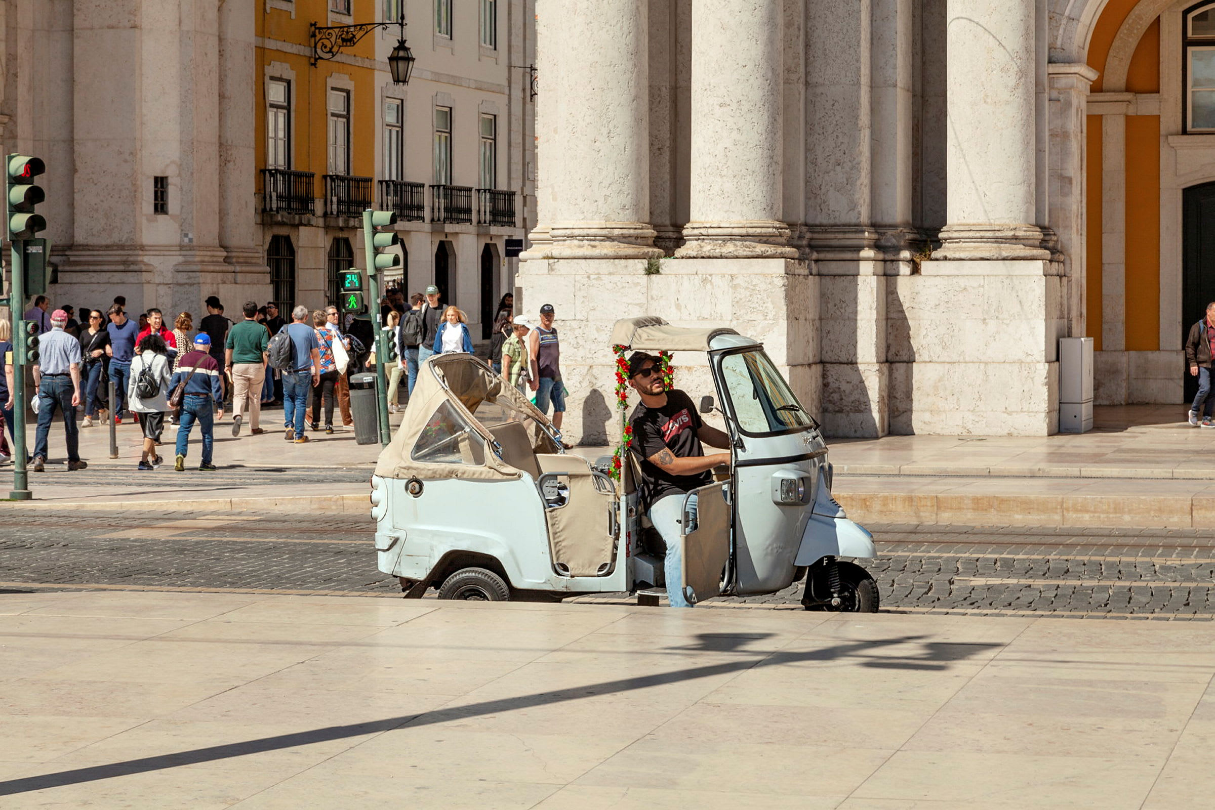 En trehjulet scooter er parkert foran en bygning med mennesker i bakgrunnen. (AI-generert tekst)