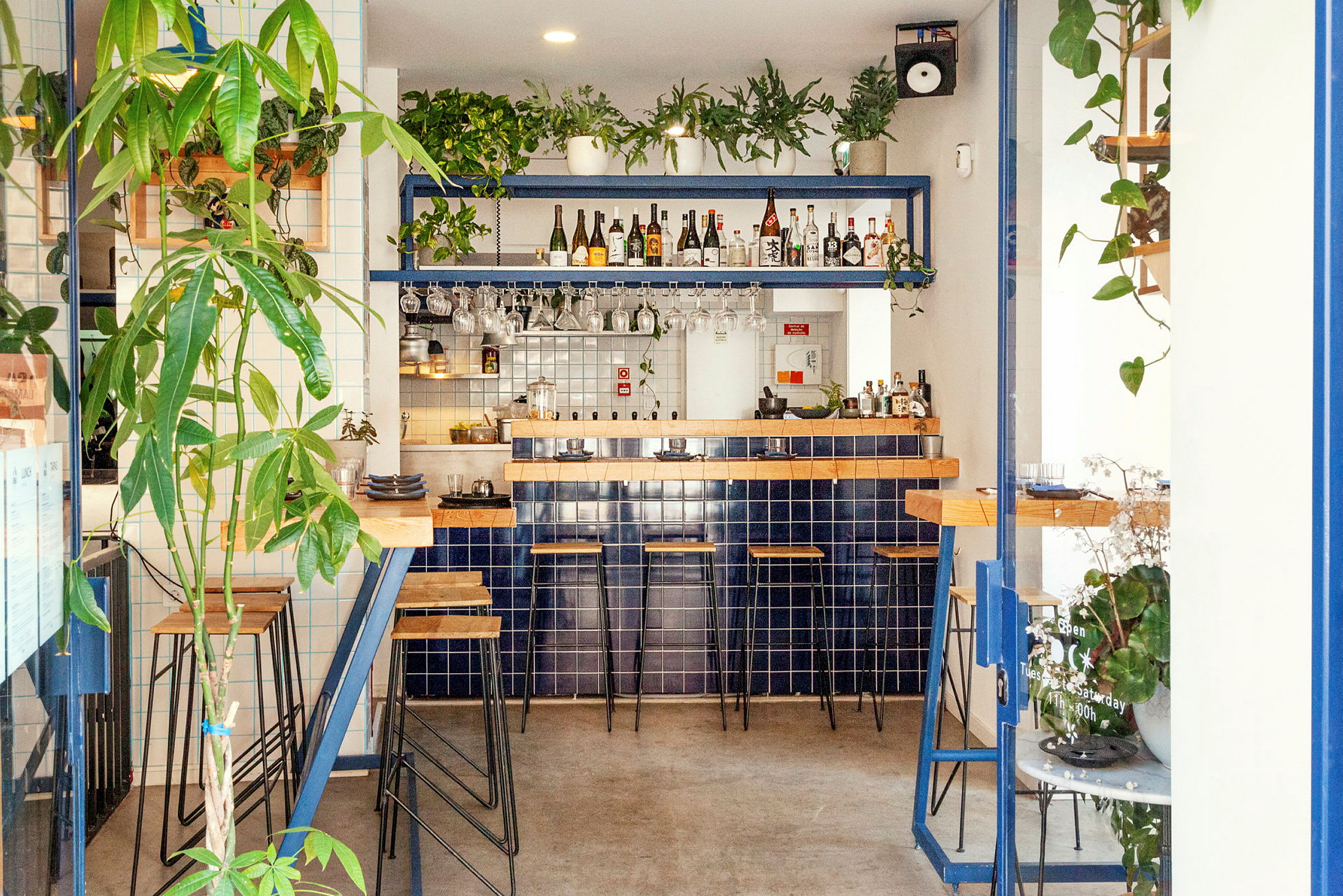 En moderne bar med blå fliser, trematerialer og grønne planter. (AI-generert tekst)