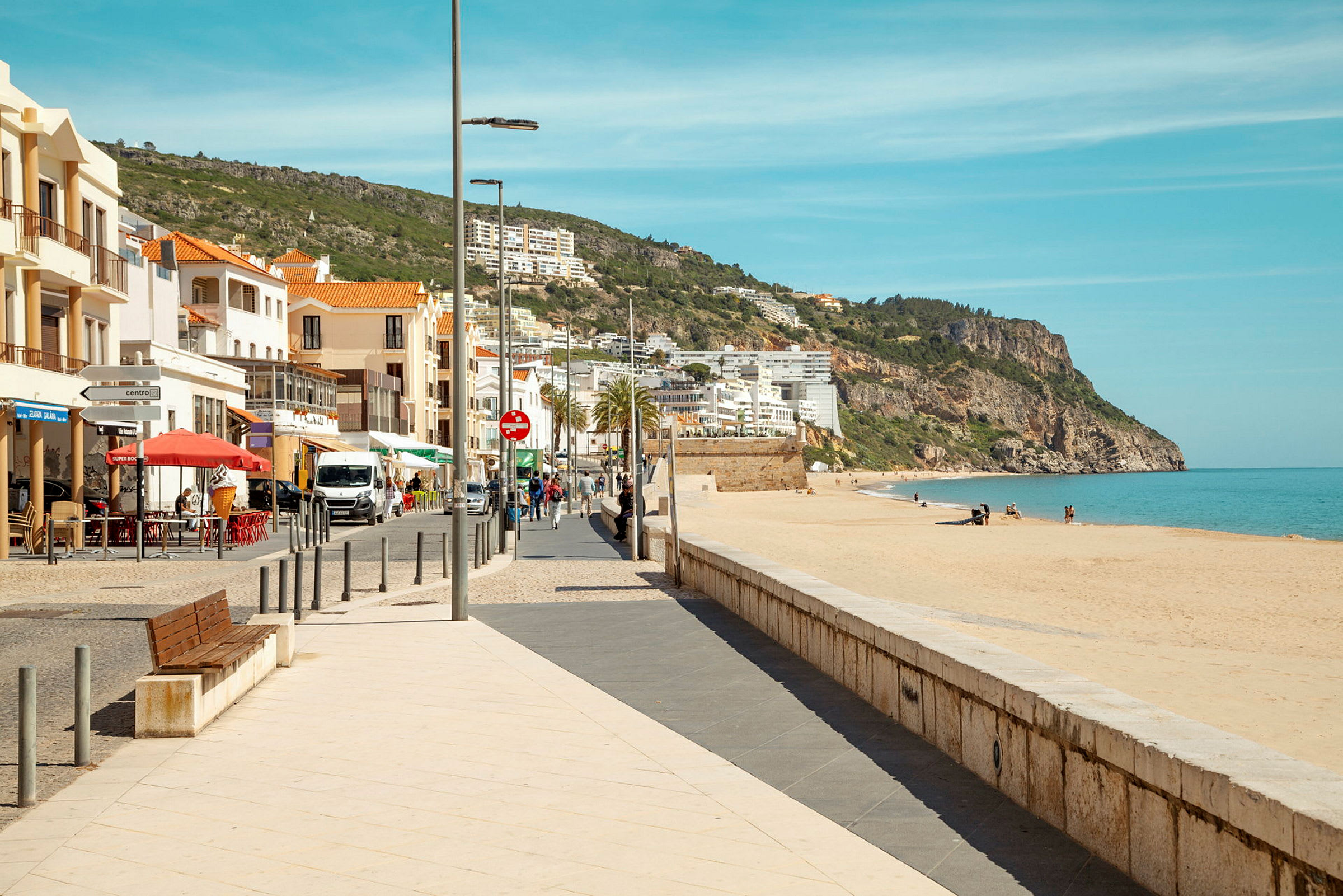 Bilde av en strandpromenade med en sandstrand og bygninger i bakgrunnen. (AI-generert tekst)