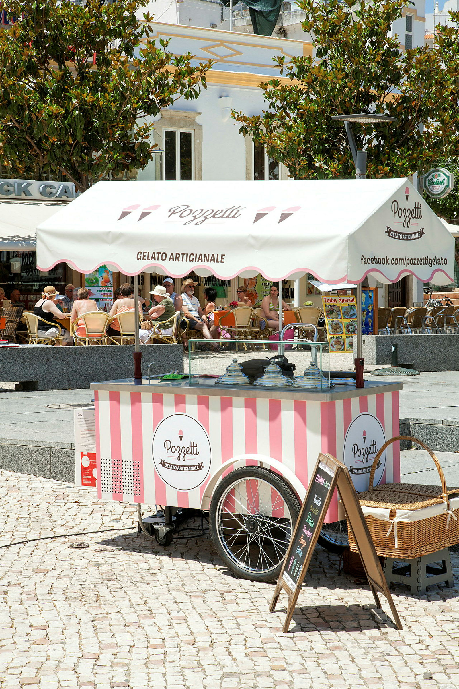 En mobil iskiosk med rosa og hvite striper under en baldakin med teksten 'Gelato Artigianale'. (AI-generert tekst)