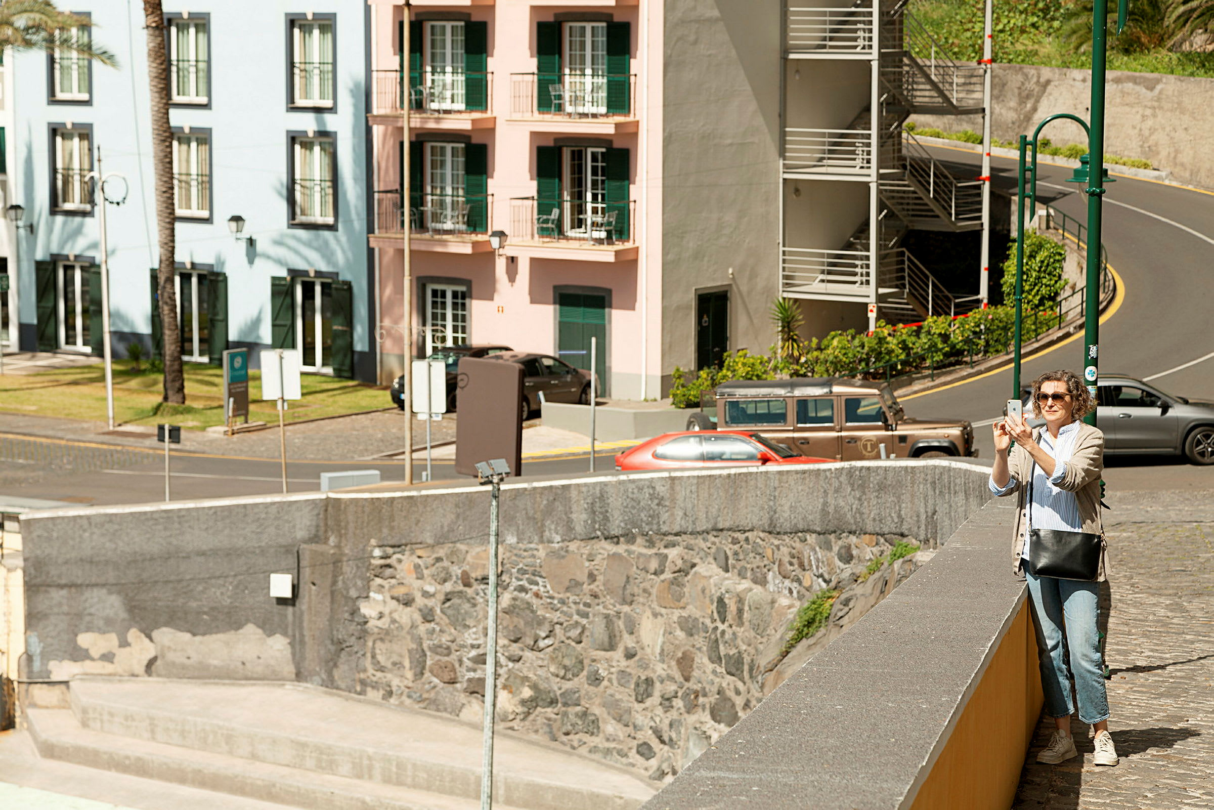 En gate med bygninger i forskjellige farger og kjøretøy parkert langs veien. (AI-generert tekst)
