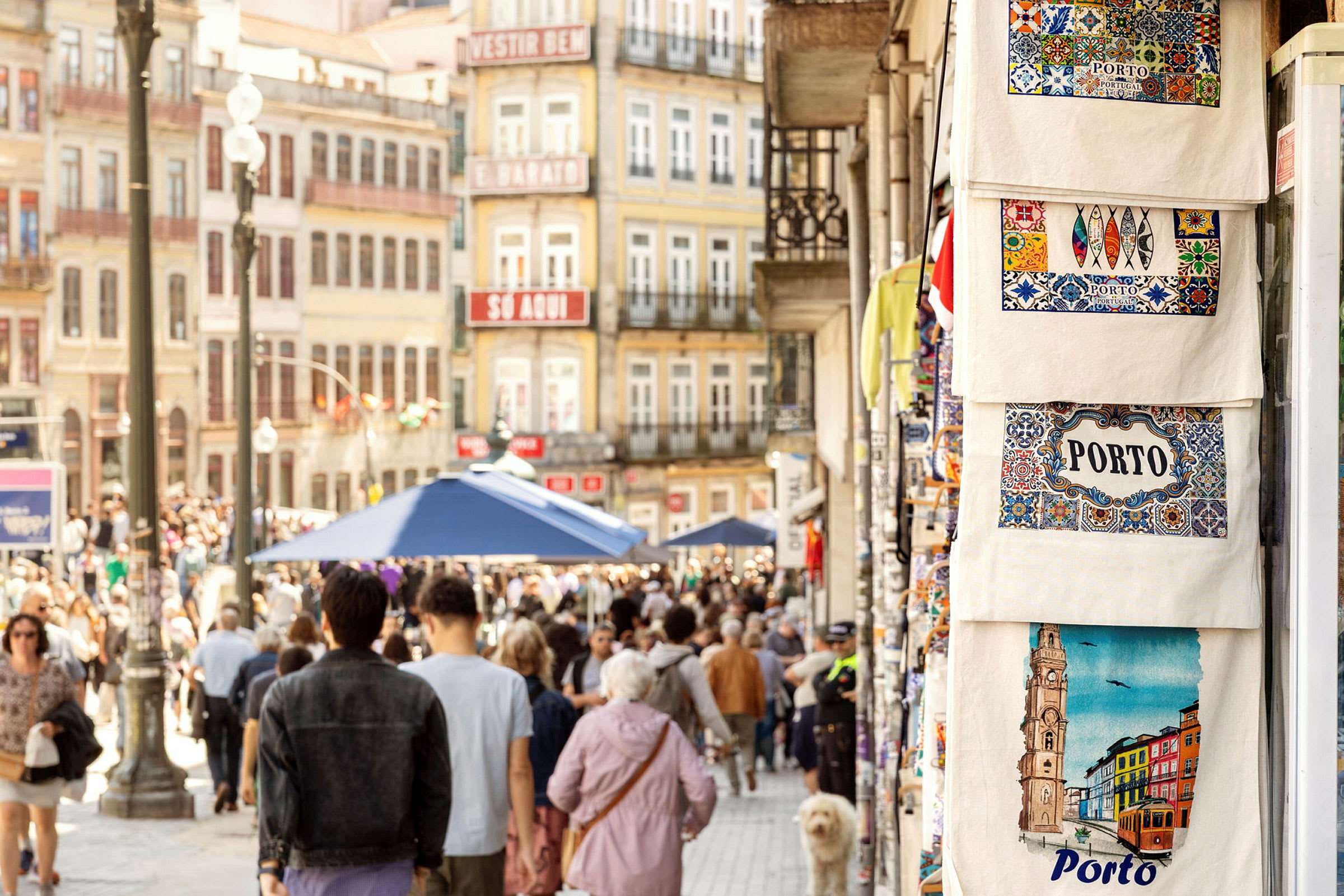Gaten i Porto med folkemengde og bygninger i bakgrunnen samt tøyvesker til salgs. (AI-generert tekst)