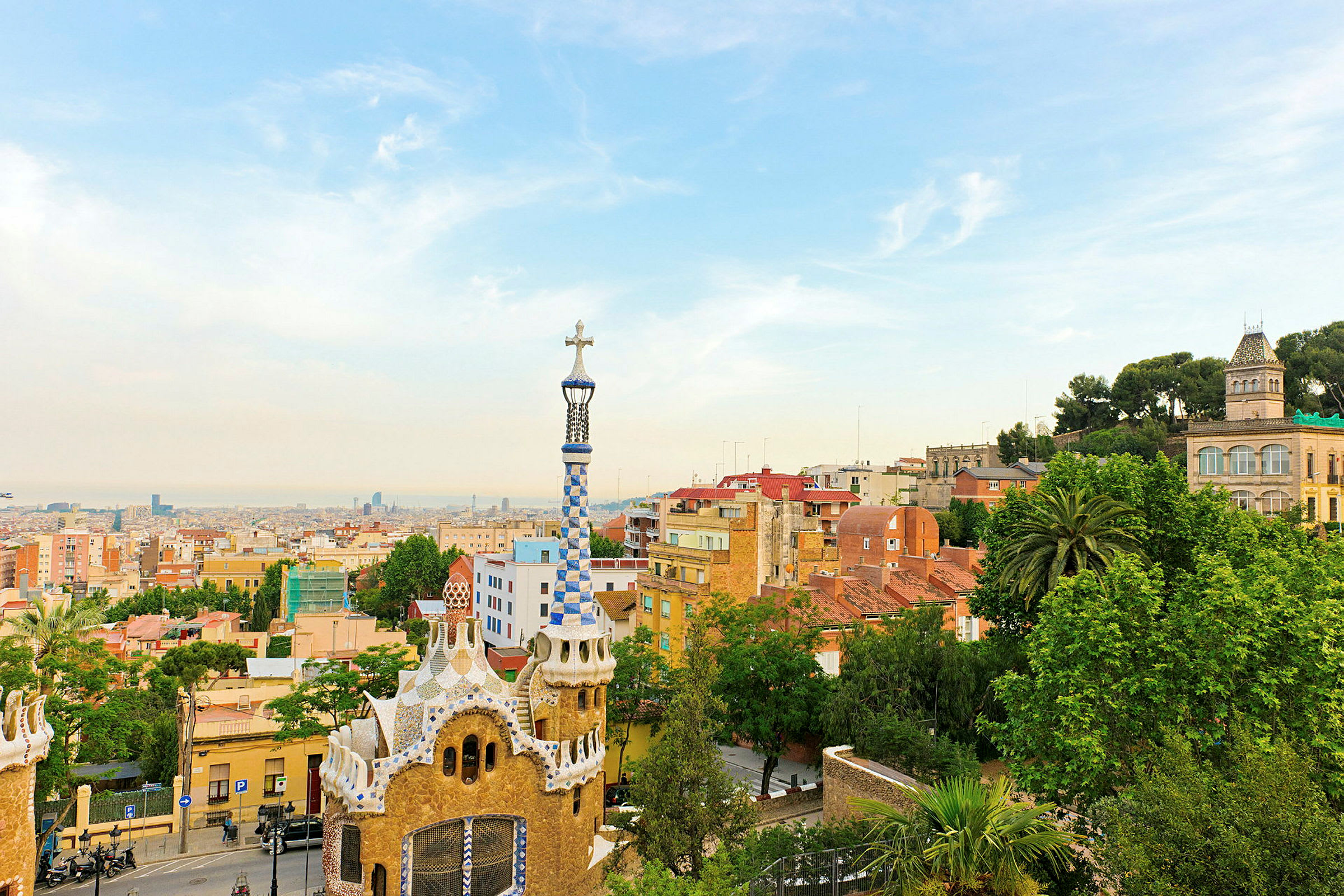 Utsikt over Park Güell i Barcelona med fargerike bygninger og byens skyline i bakgrunnen. (AI-generert tekst)