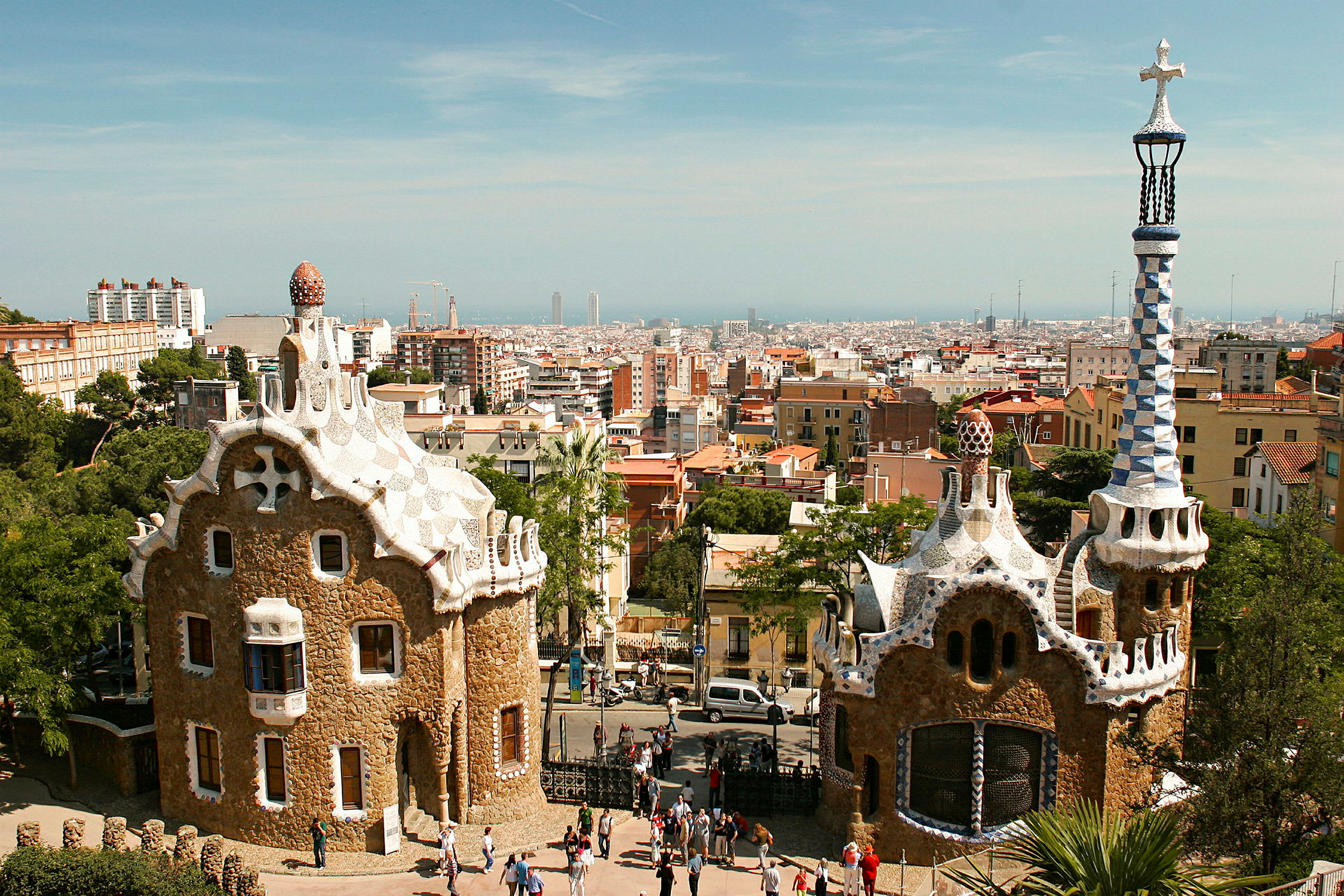 Bilde av to unike bygninger i Park Güell, Barcelona, med byen i bakgrunnen. (AI-generert tekst)