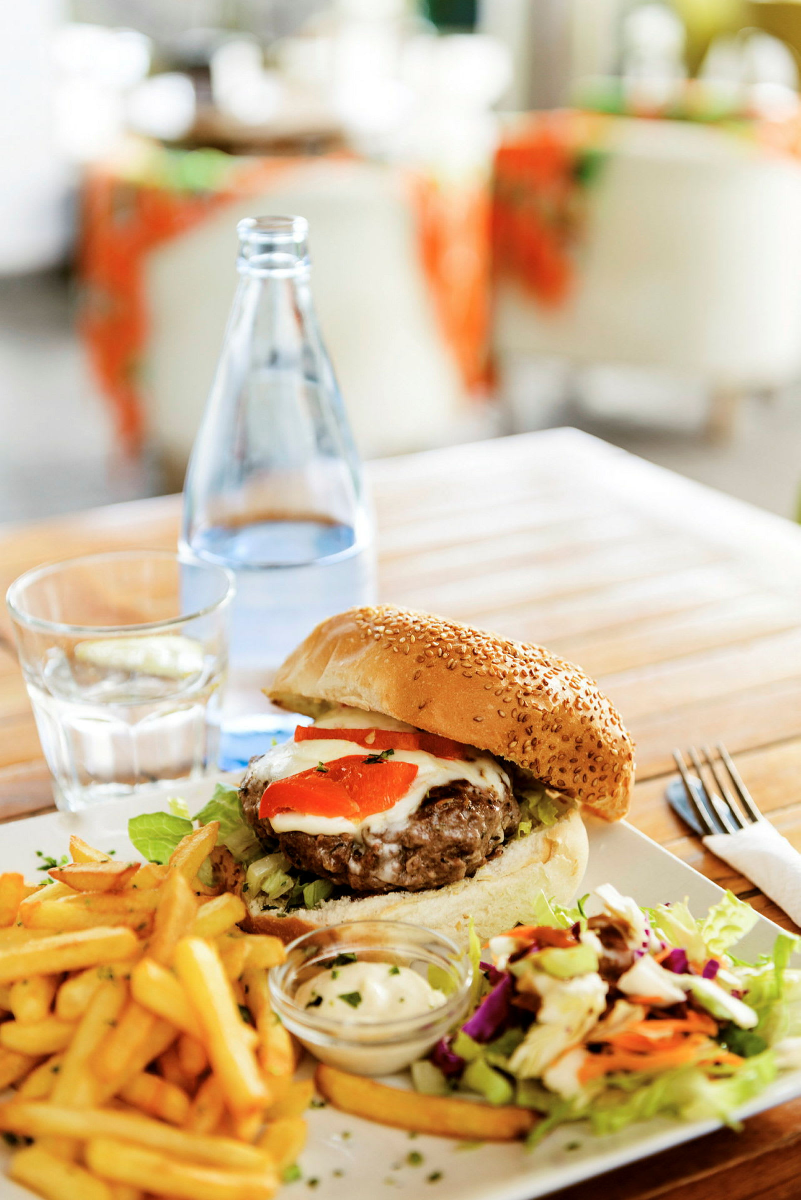 Tallerken med hamburger, pommes frites, salat og saus servert på et trebord. (AI-generert tekst)