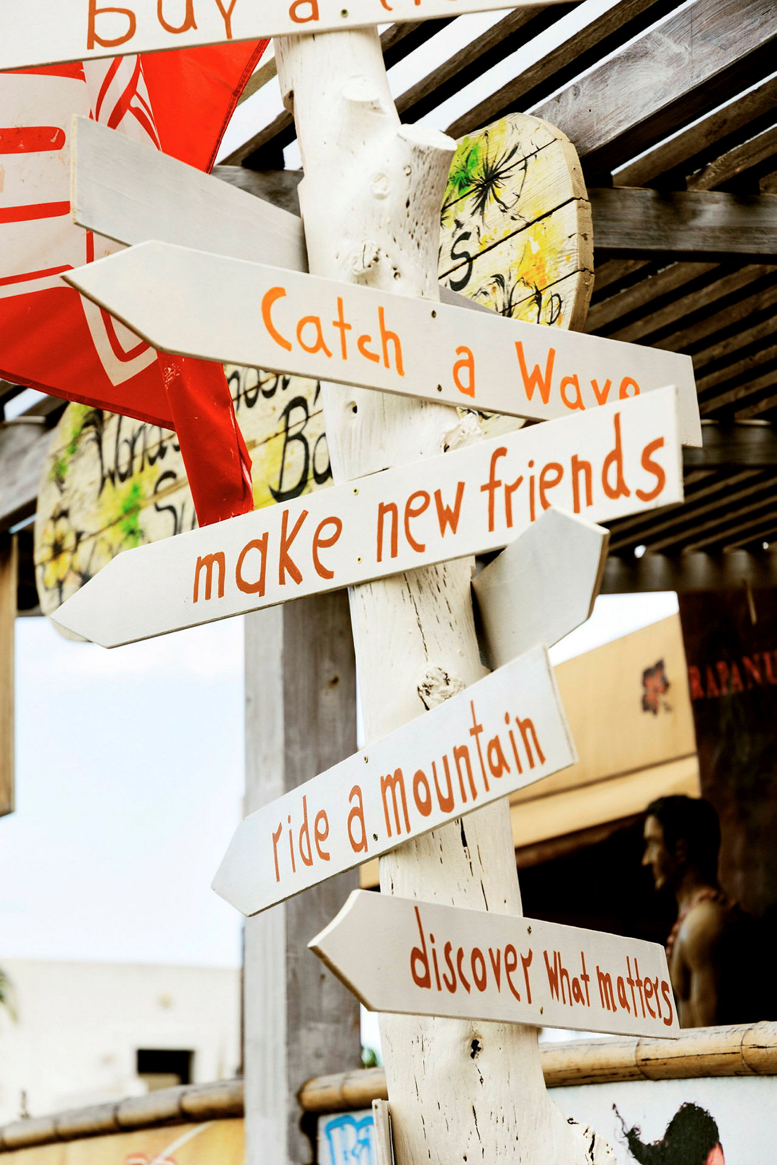 Et treskilt med flere piler som peker i forskjellige retninger og tekster som "Catch a Wave", "Make new friends", "Ride a mountain" og "Discover what matters". (AI-generert tekst)