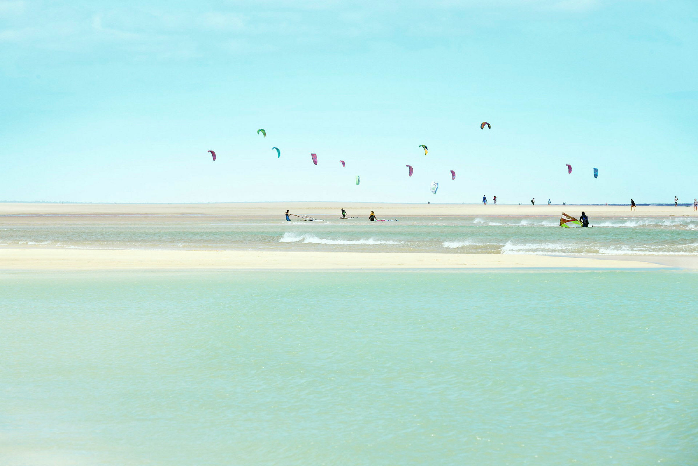 Strand med personer som driver med kitesurfing. (AI-generert tekst)