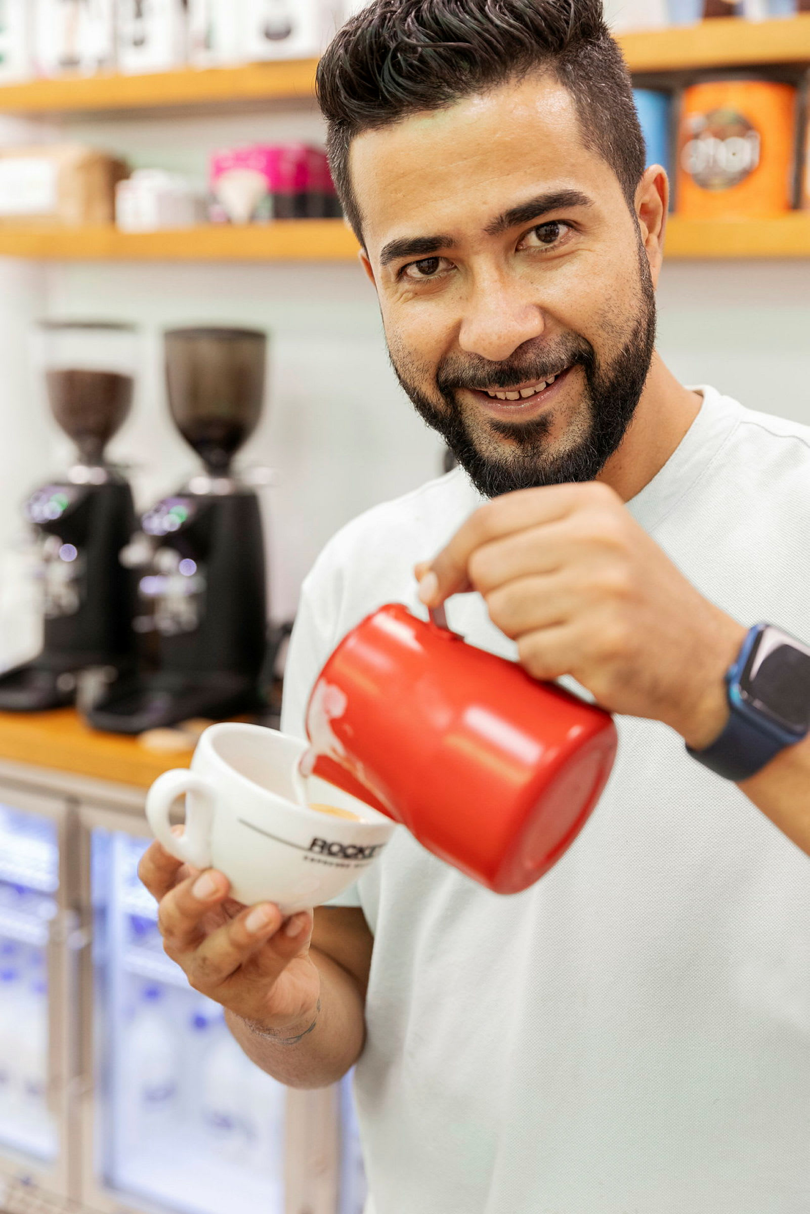 Personen heller melk i en kaffekopp med en rød kanne. (AI-generert tekst)