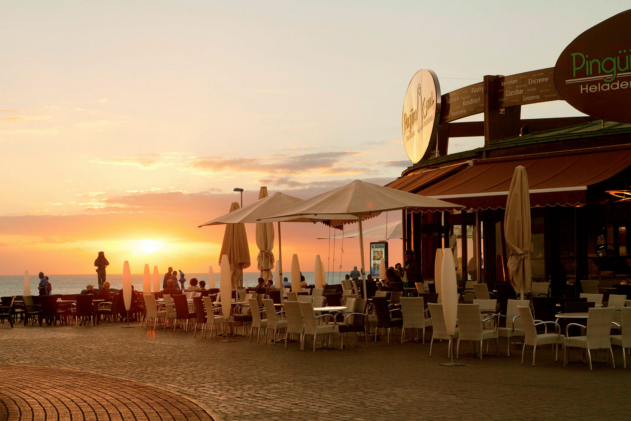 Utendørs sitteplass på en restaurant ved solnedgang. (AI-generert tekst)