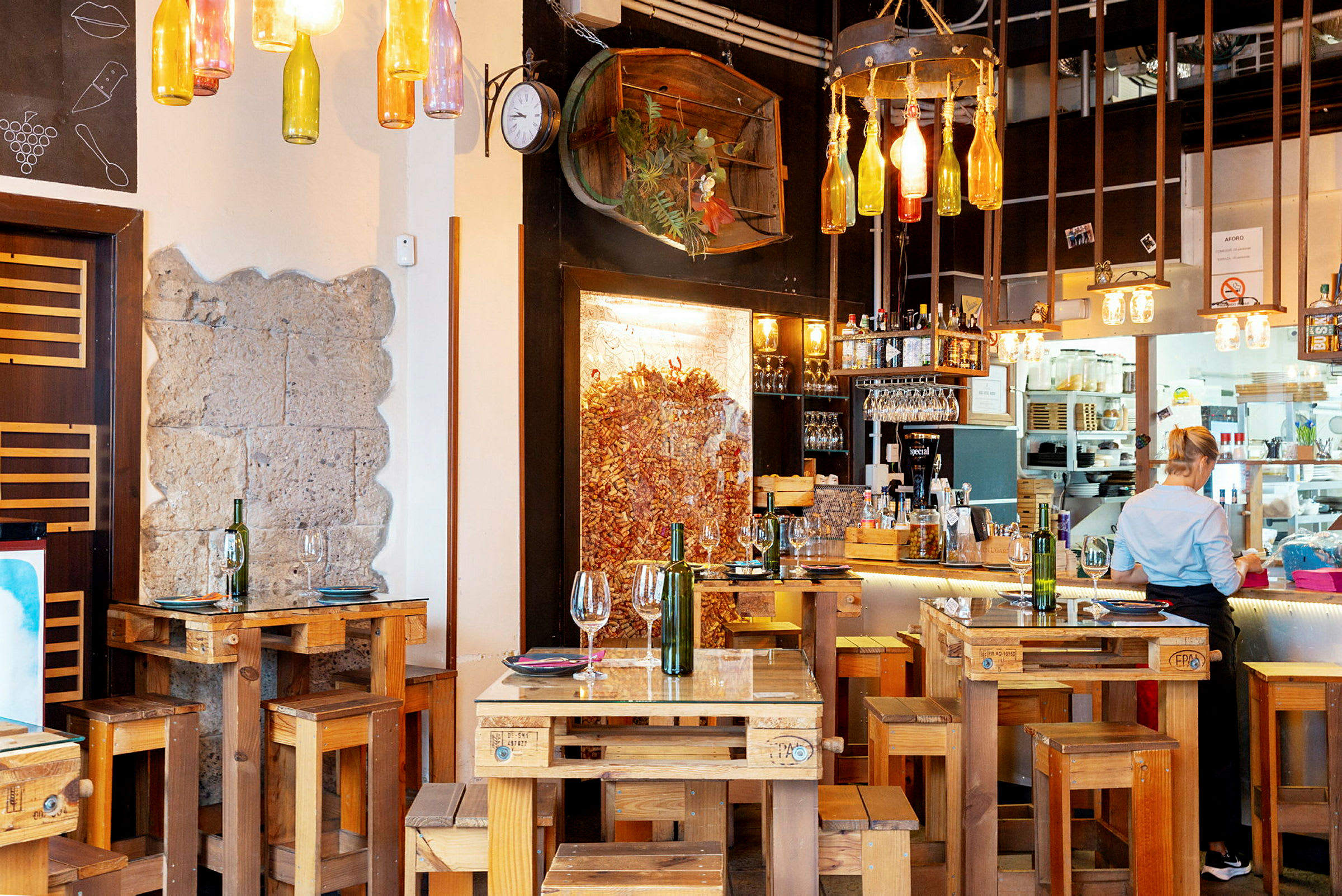 Restaurant med rustikke tremøbler og dekorative flasker hengende fra taket. (AI-generert tekst)