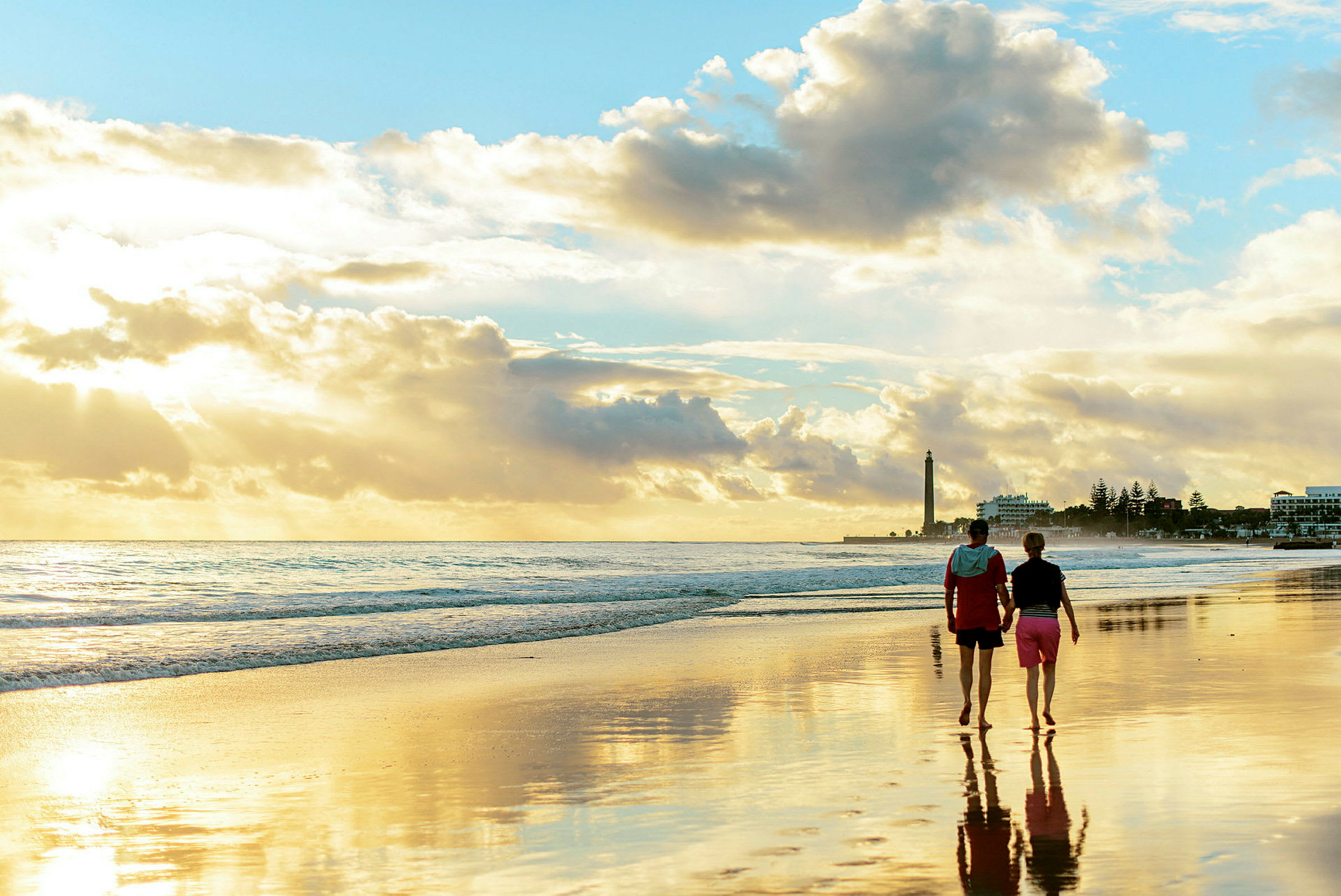 To personer går langs en strand ved solnedgang. (AI-generert tekst)